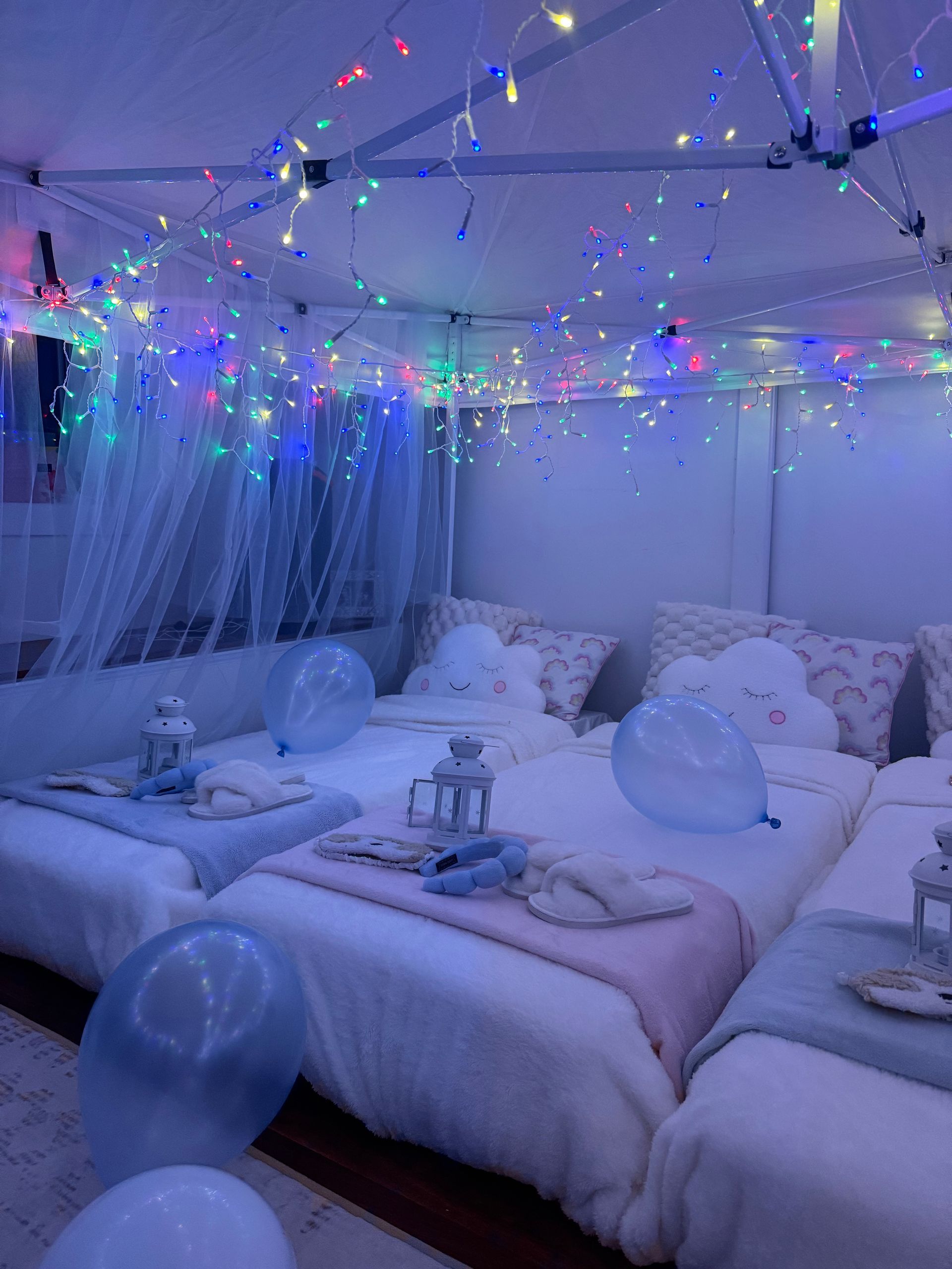 Twinkling fairy-lit bedroom with white canopy bed, soft blue decor, and balloons on the floor and bed — Sweet Parties & Braids in Tatton, NSW