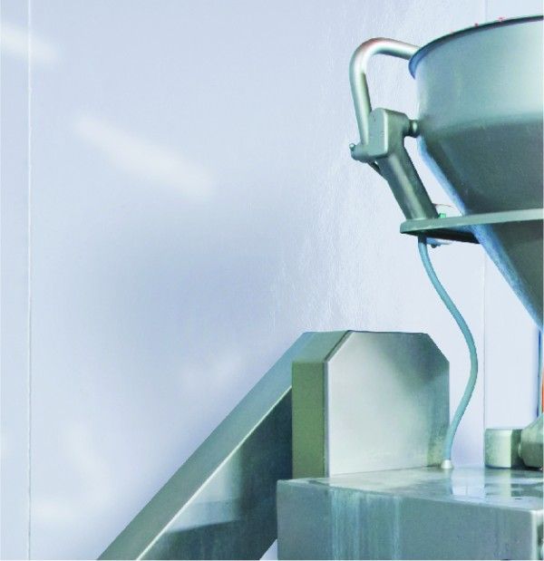 A stainless steel container with a handle sits on a table