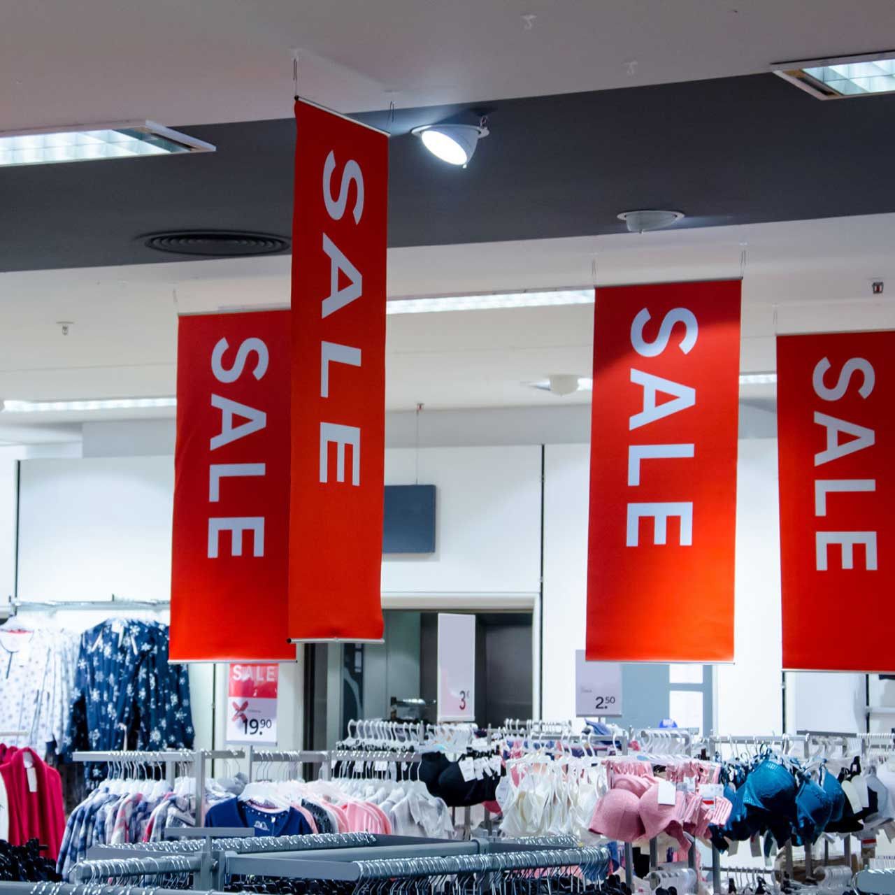 Several red sale banners hang from the ceiling of a store