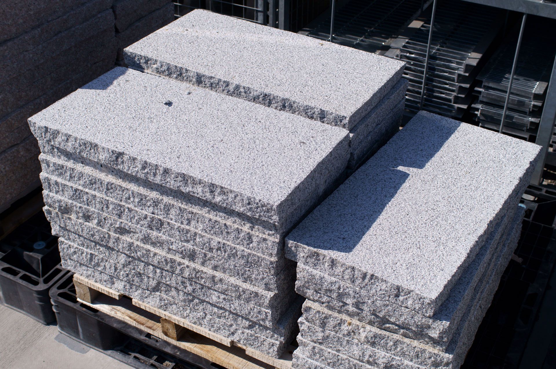 Stacks of gray concrete slabs on a wooden pallet in an outdoor storage area