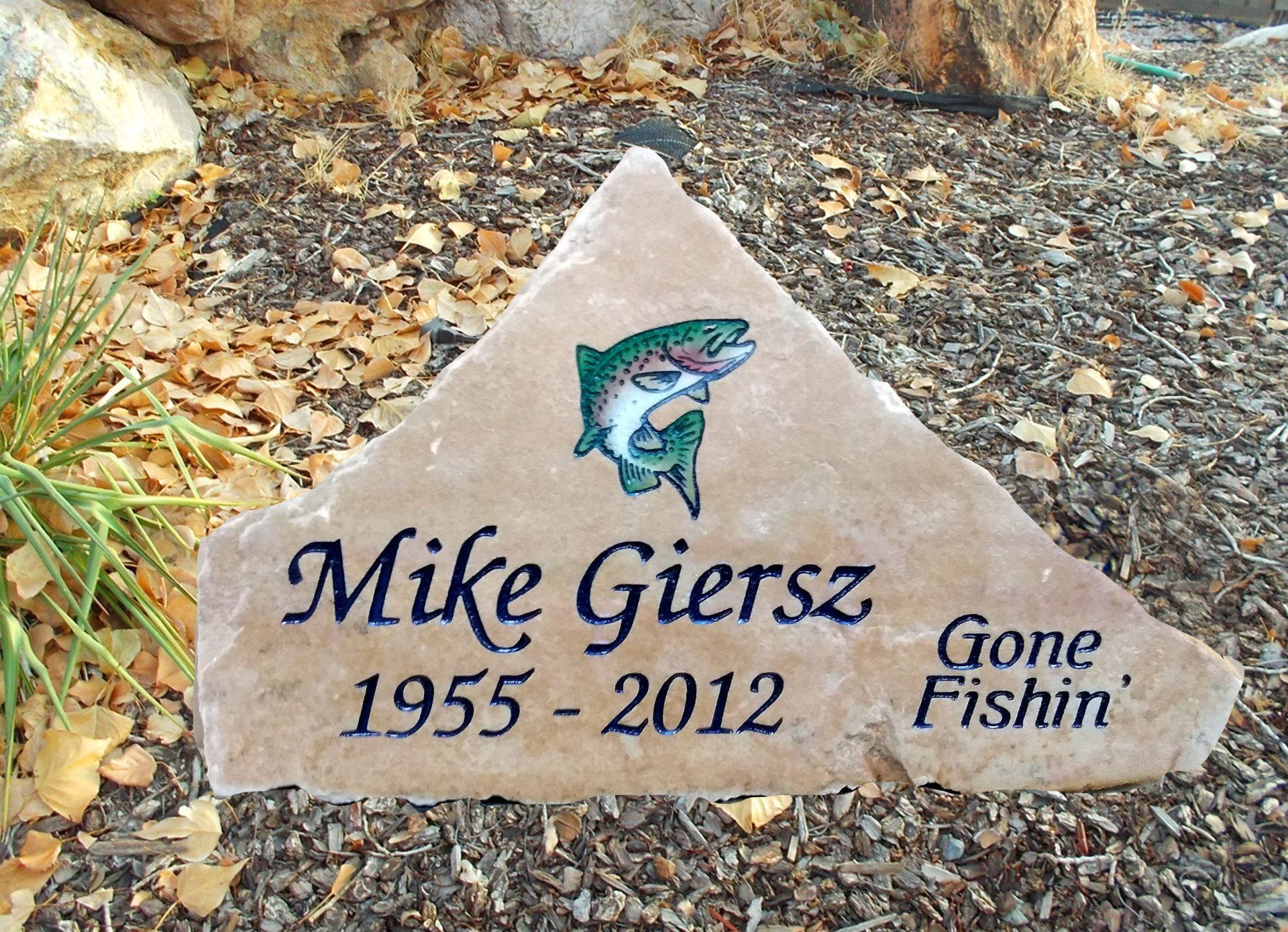 Memorial stone for Mike Gierz, 1955–2012, with fish graphic and “Gone Fishin’” inscription
