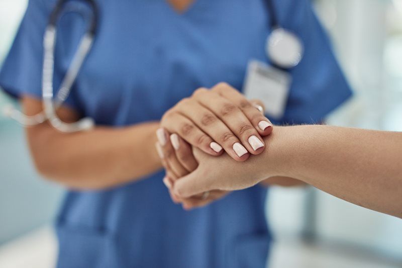 A nurse is holding a patient 's hand in a hospital.