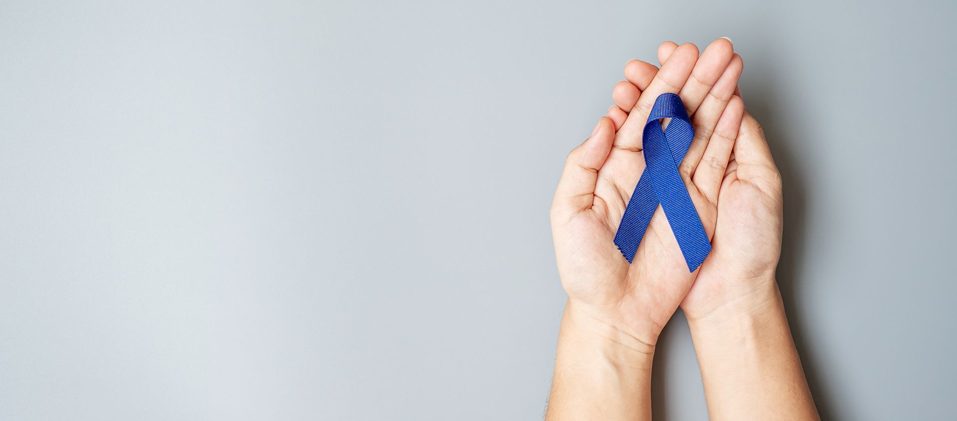 Hands holding a blue ribbon.