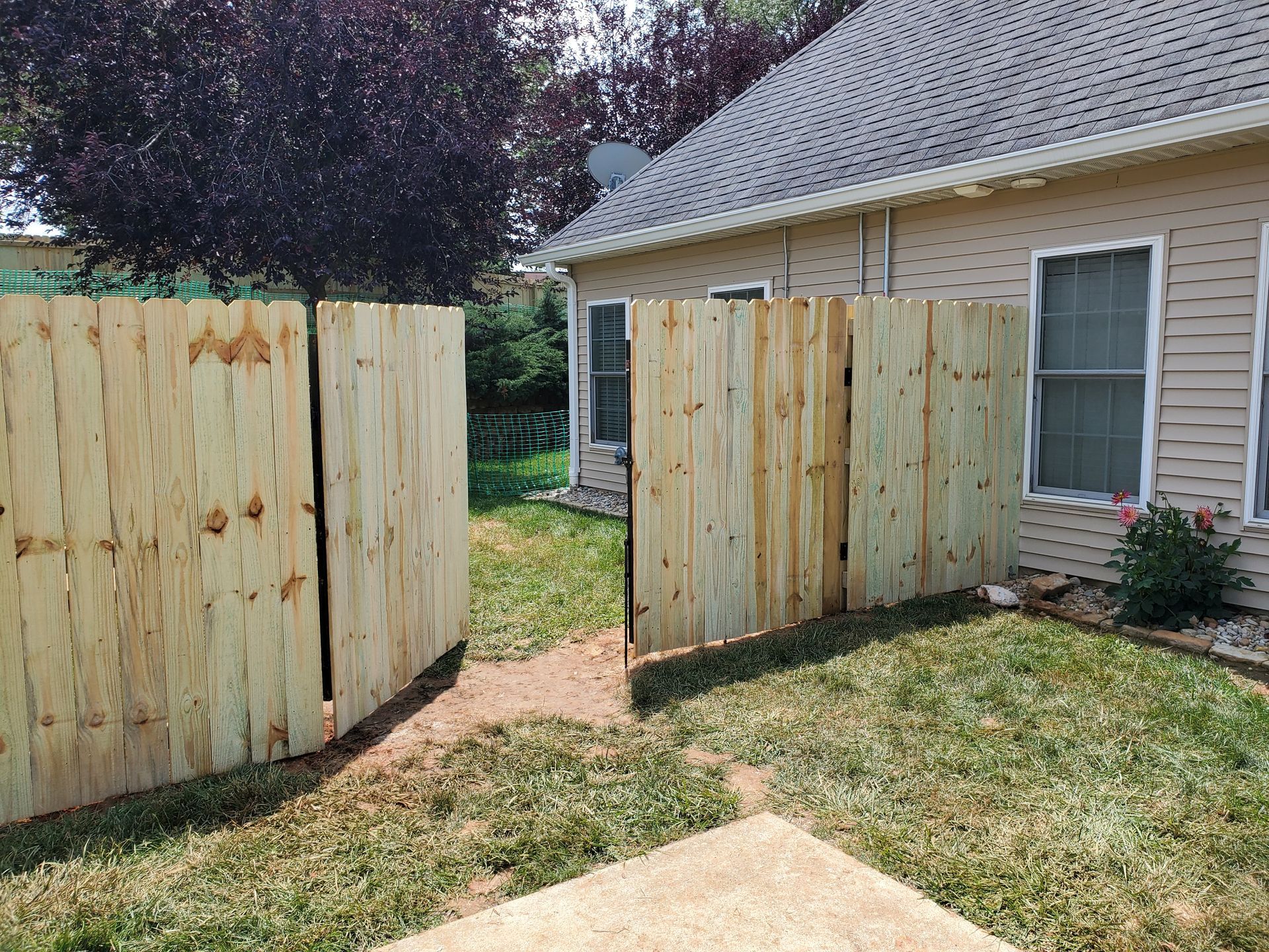 Wooden fence sections surrounding a home, with an opening leading to a yard.