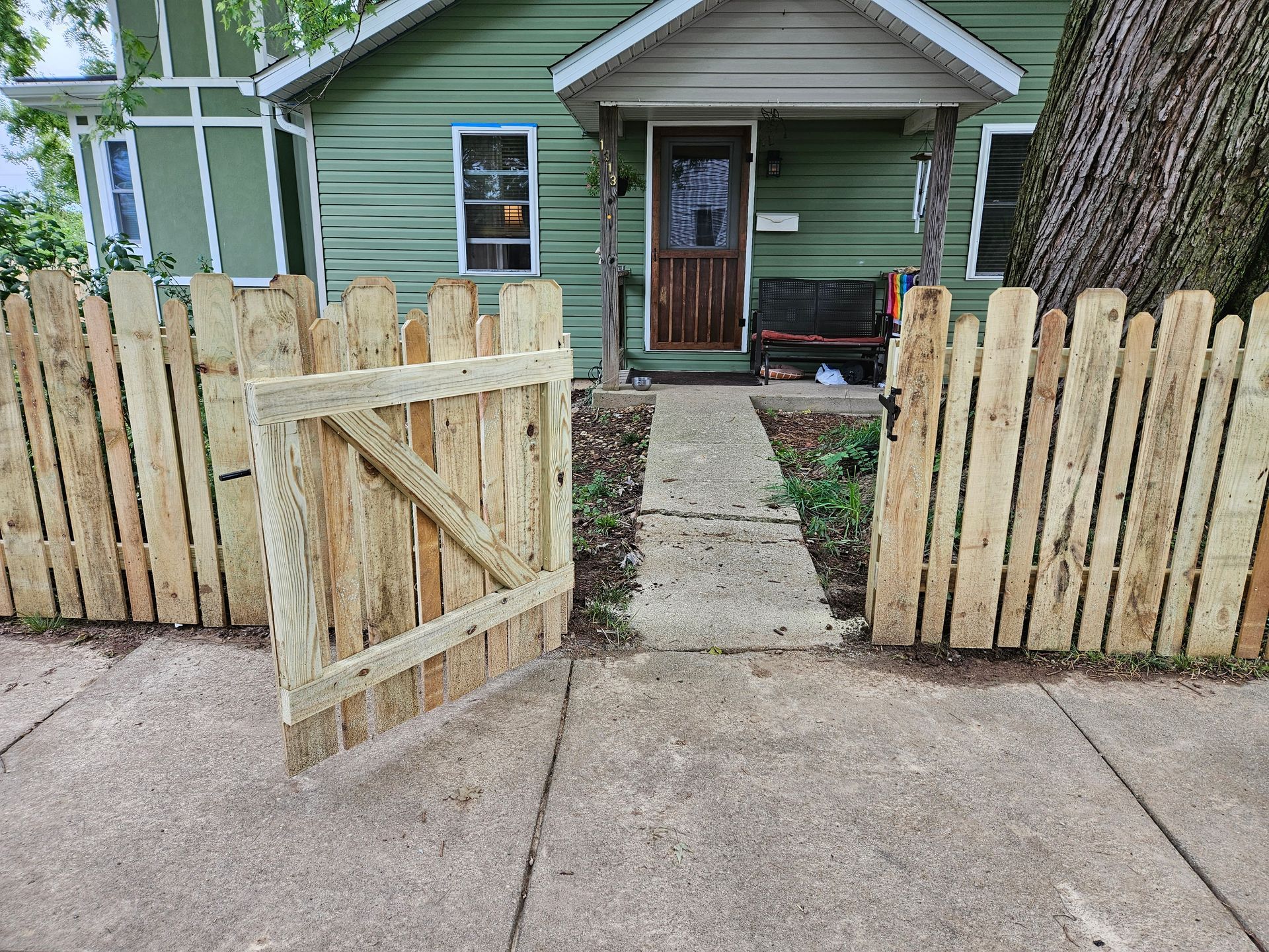Wooden fence with gate leading to a green house.
