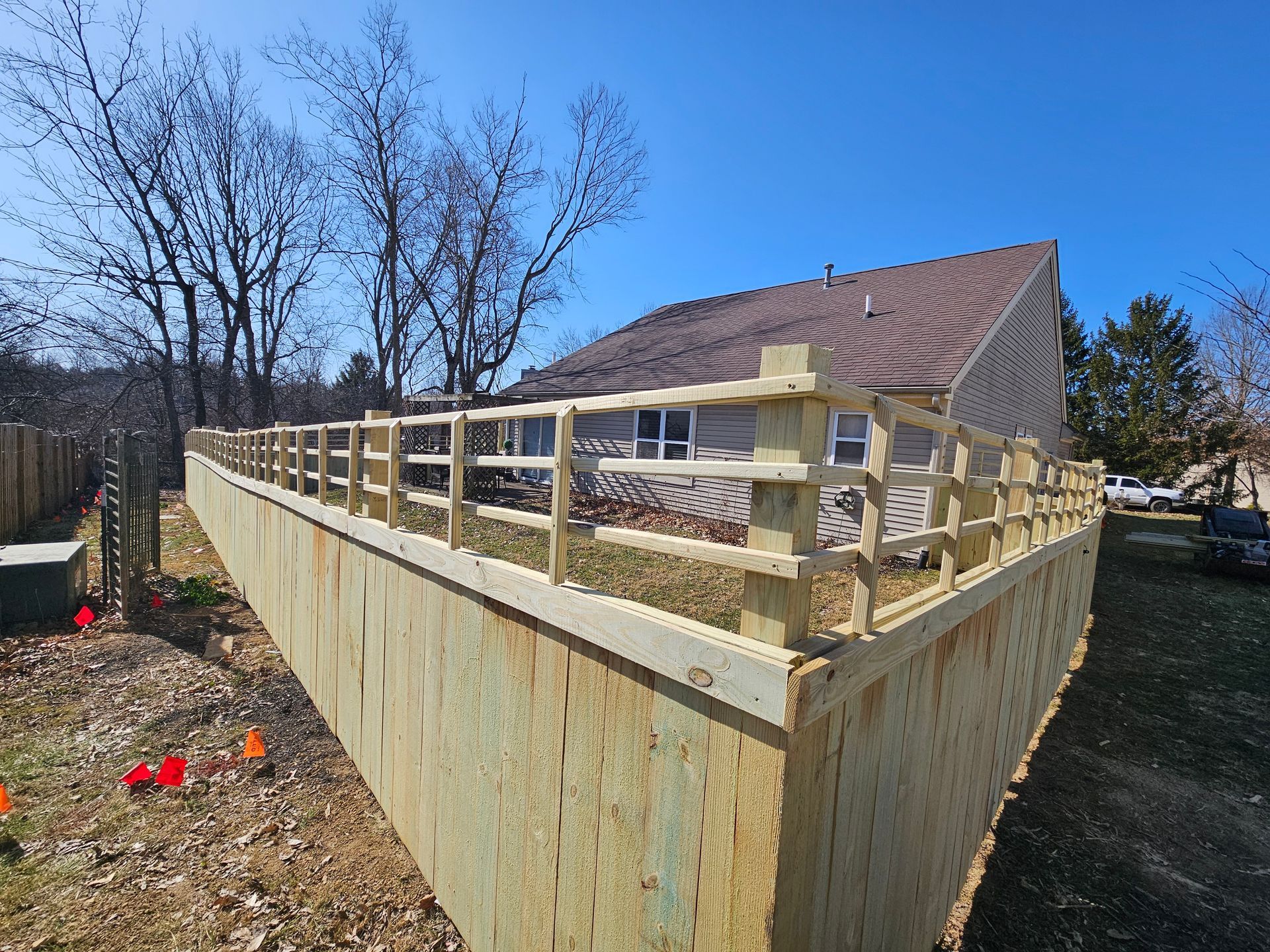 Wooden fence along a retaining wall, sunny outdoor setting.