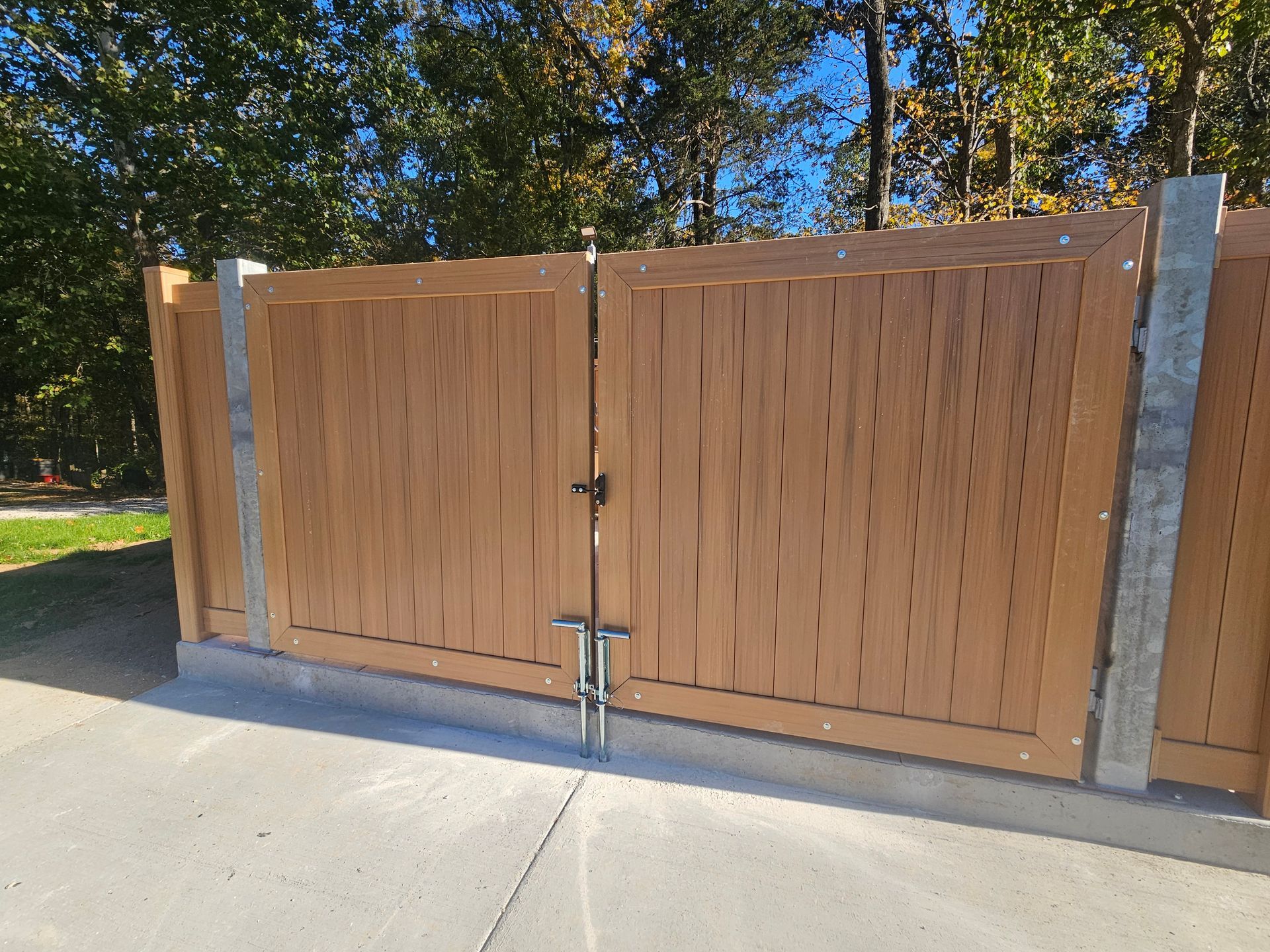 Brown wooden gate and fence with concrete posts.