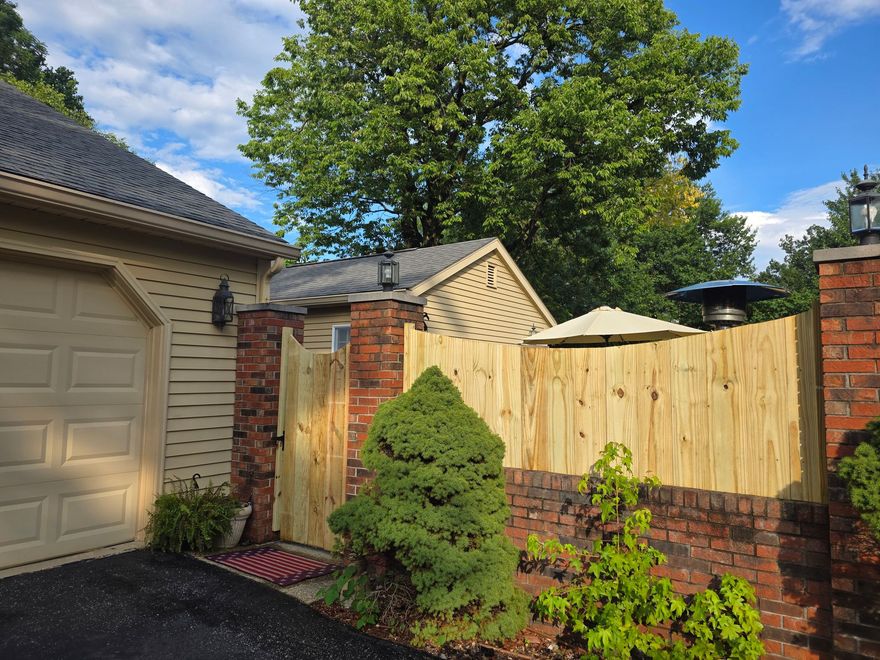 Brown wooden gate and fence with concrete posts.