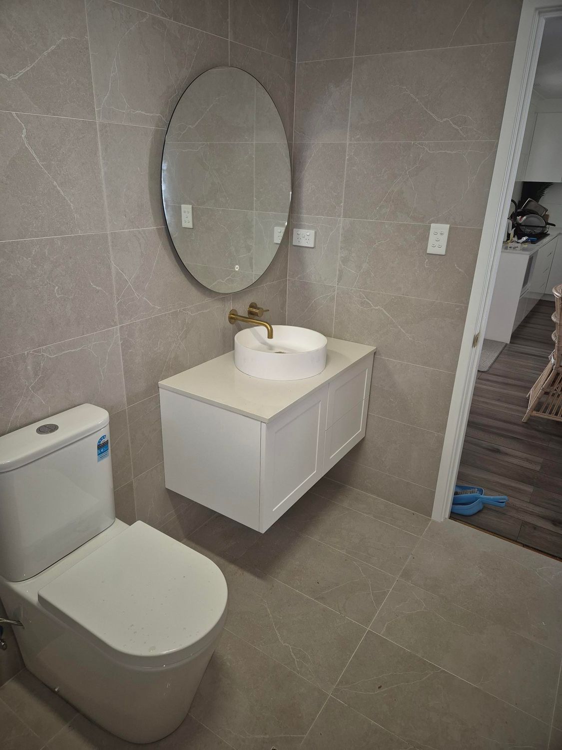 A Man Is Kneeling On The Floor Working On Pipes — Bennett Plumbing In Broughton Village, NSW