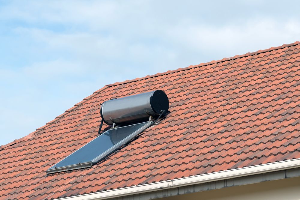 A Solar Water Heater Is Mounted On The Roof Of A House — Bennett Plumbing In Broughton Village, NSW