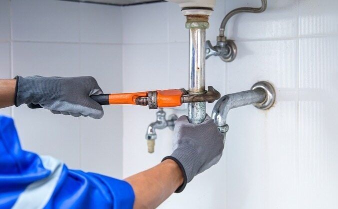 A Plumber Is Fixing A Sink Pipe With A Wrench — Bennett Plumbing In Broughton Village, NSW