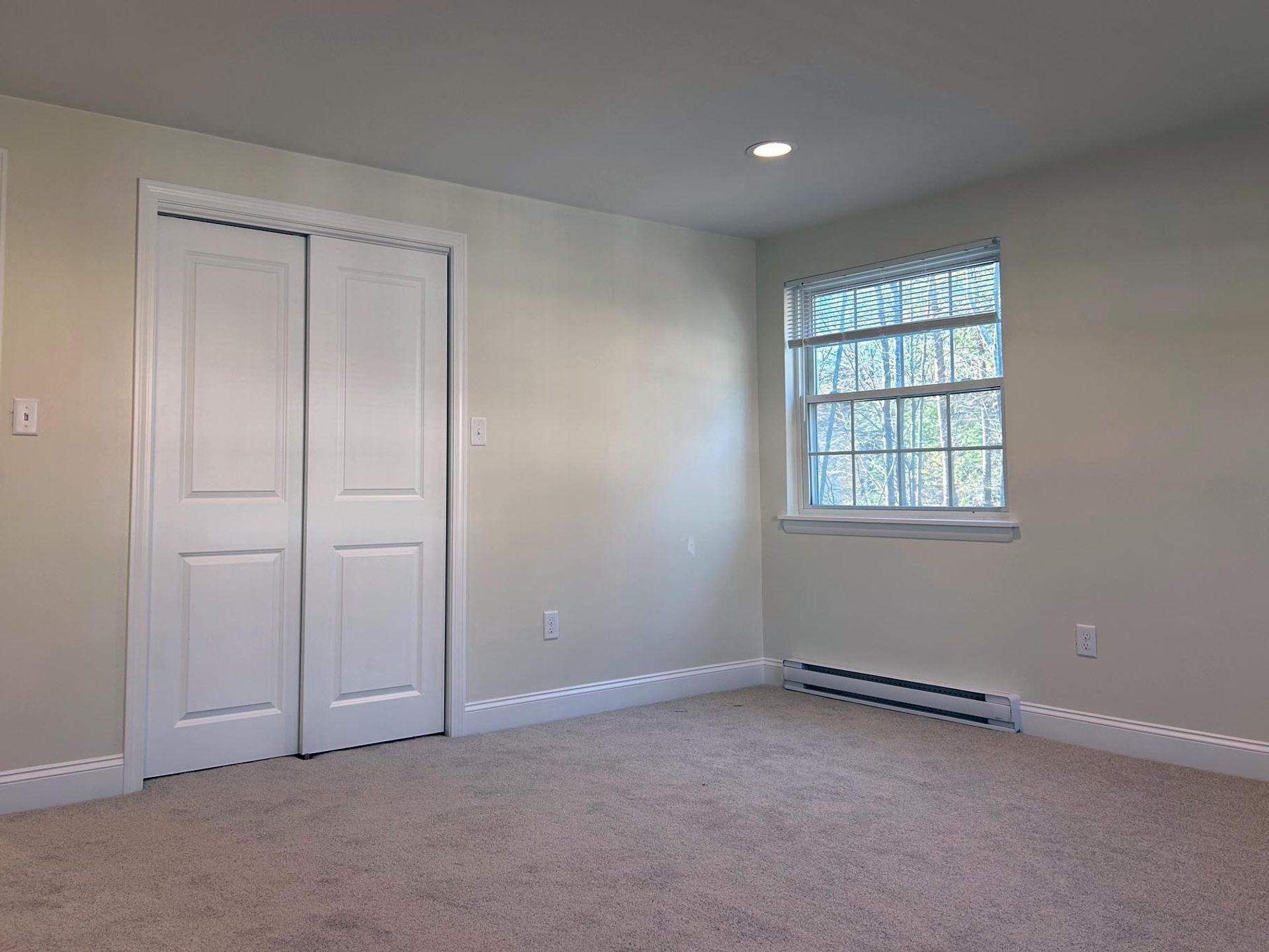An empty bedroom with a window and sliding doors.