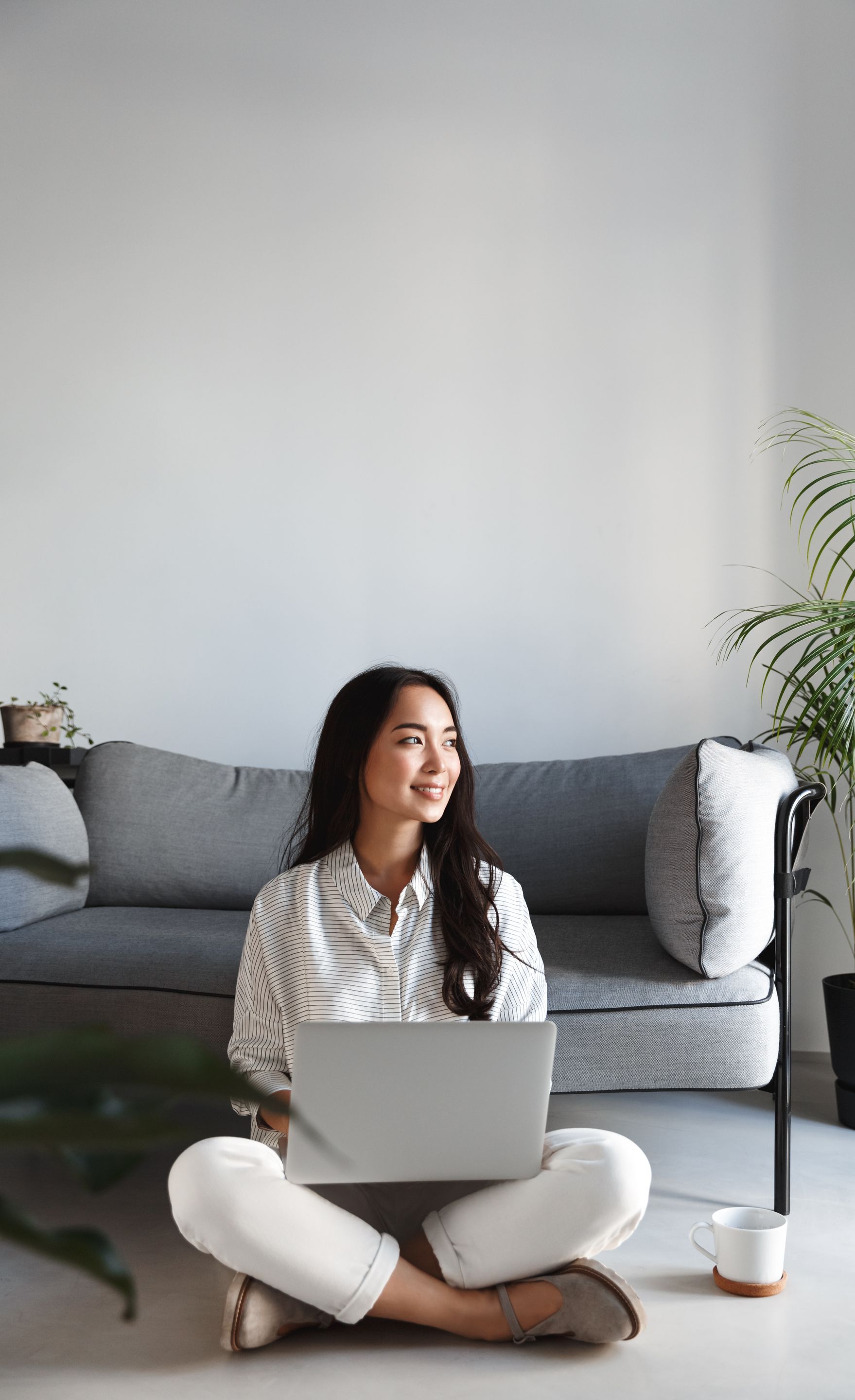 A woman is sitting on the floor using a laptop computer.
