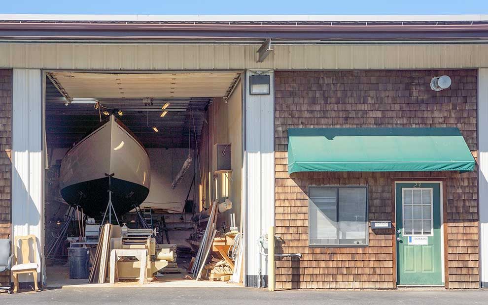 A boat is in a garage with the door open.