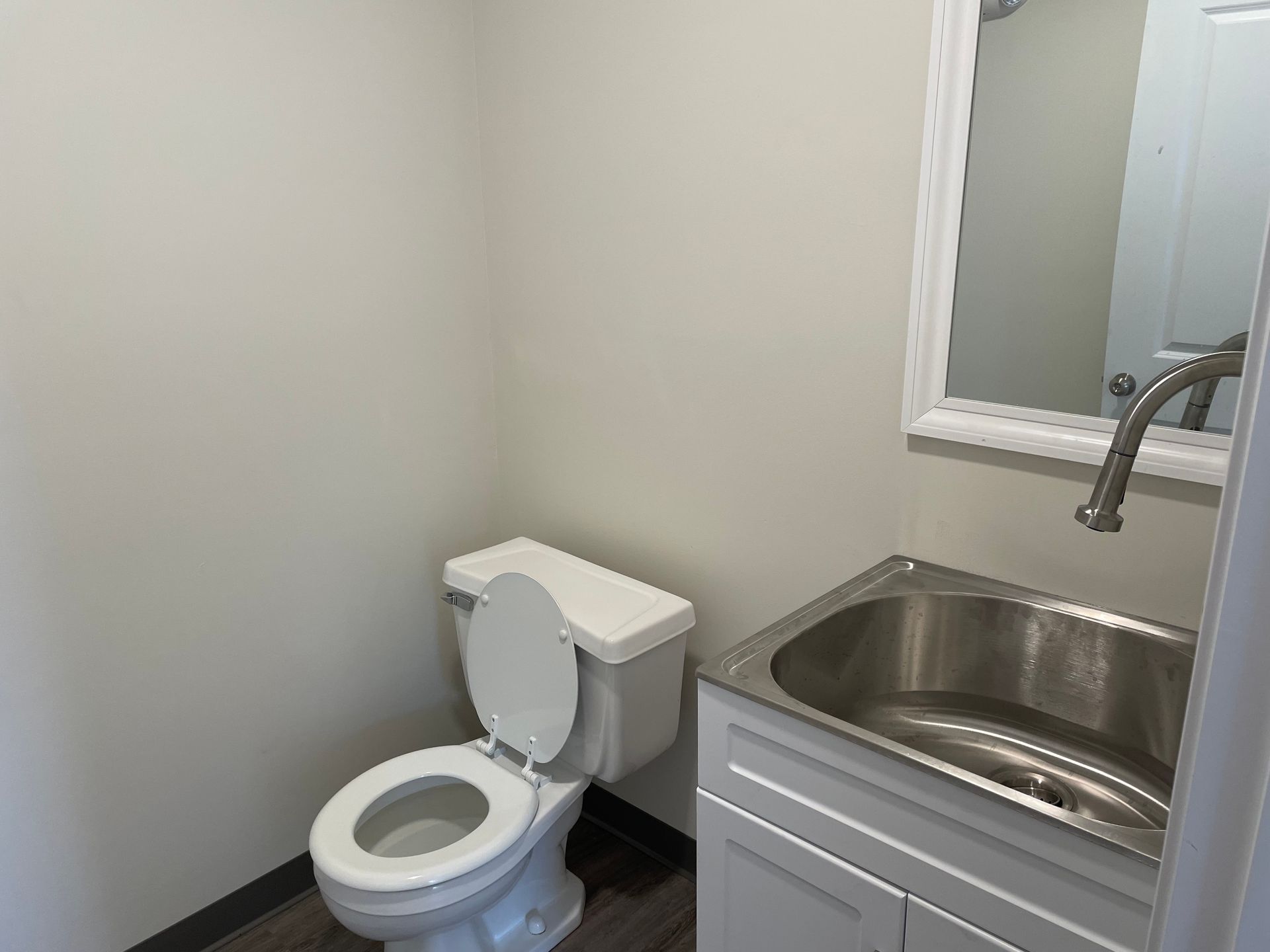 A bathroom with a toilet , sink and mirror.