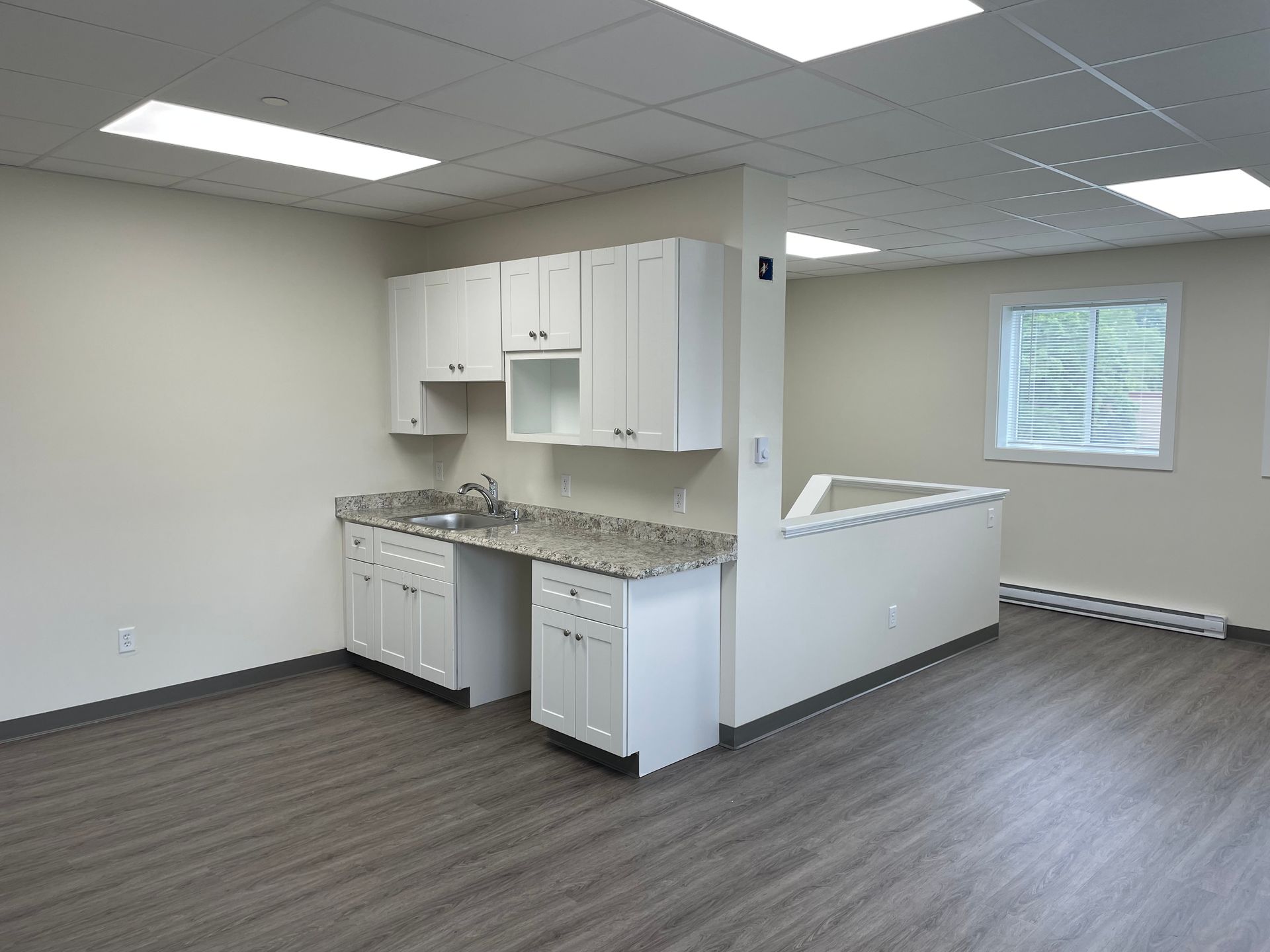 An empty kitchen with white cabinets and granite counter tops.