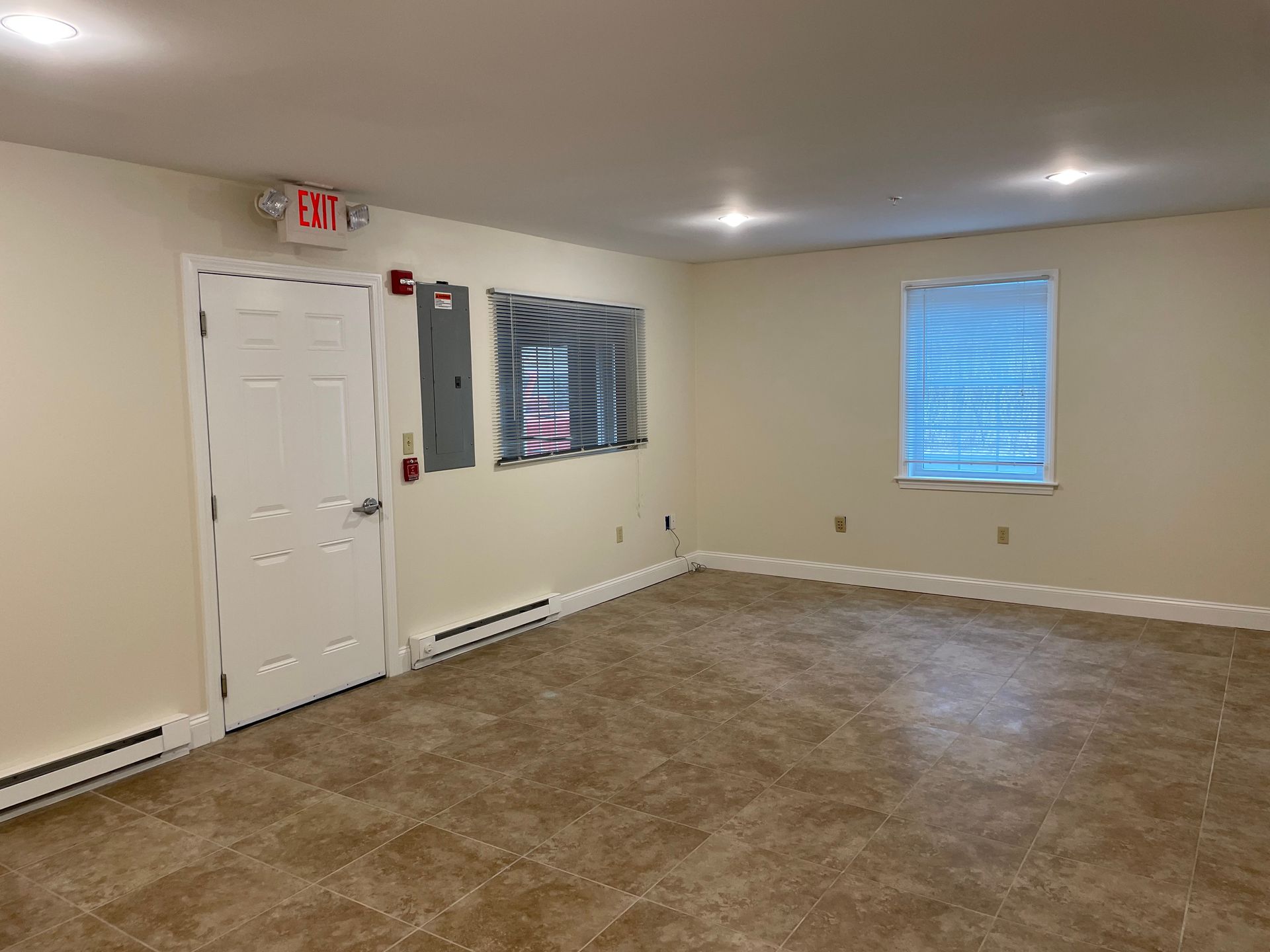 A large empty room with a fire exit sign on the ceiling.