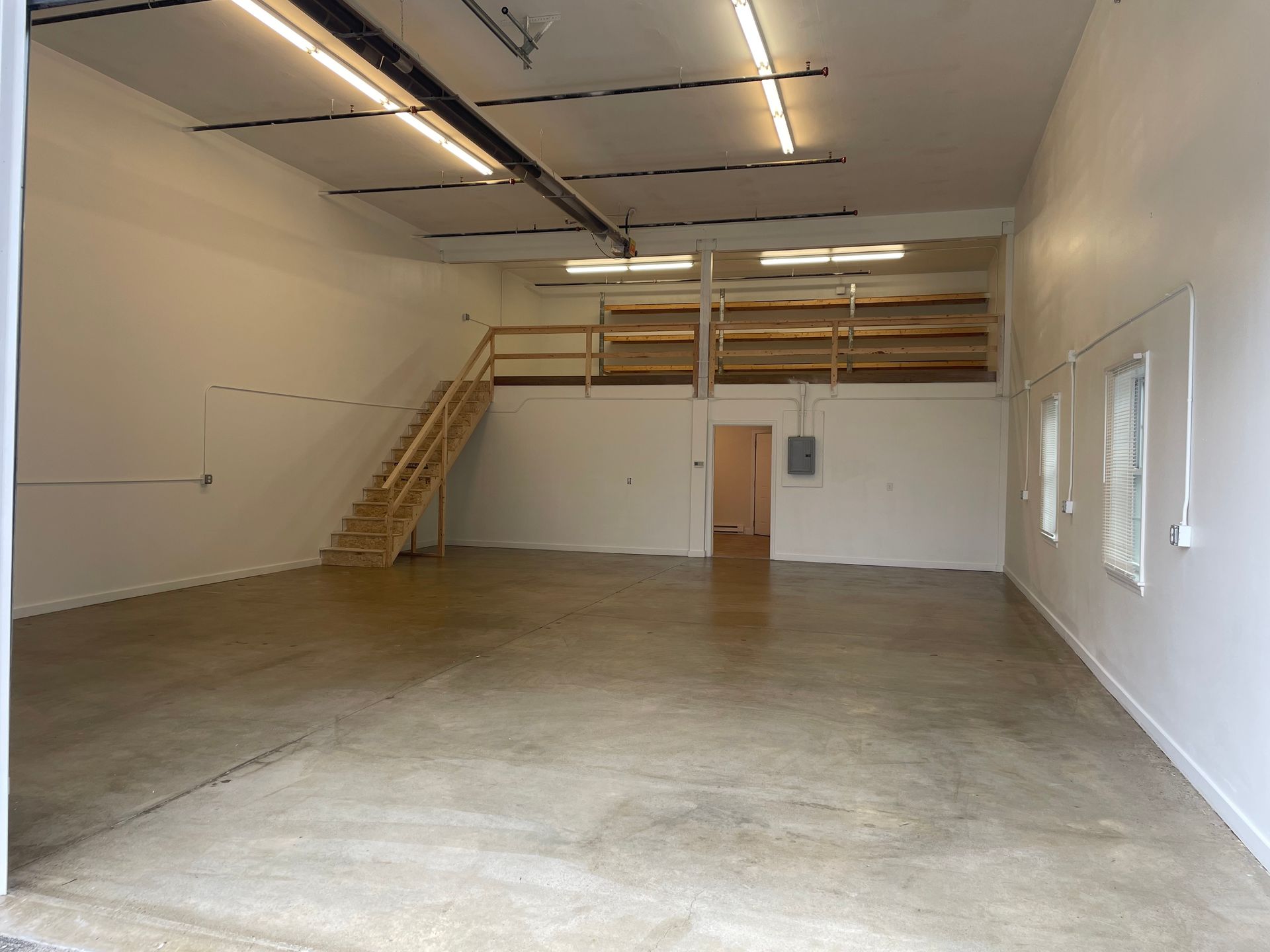 A large empty room with a staircase leading to the second floor