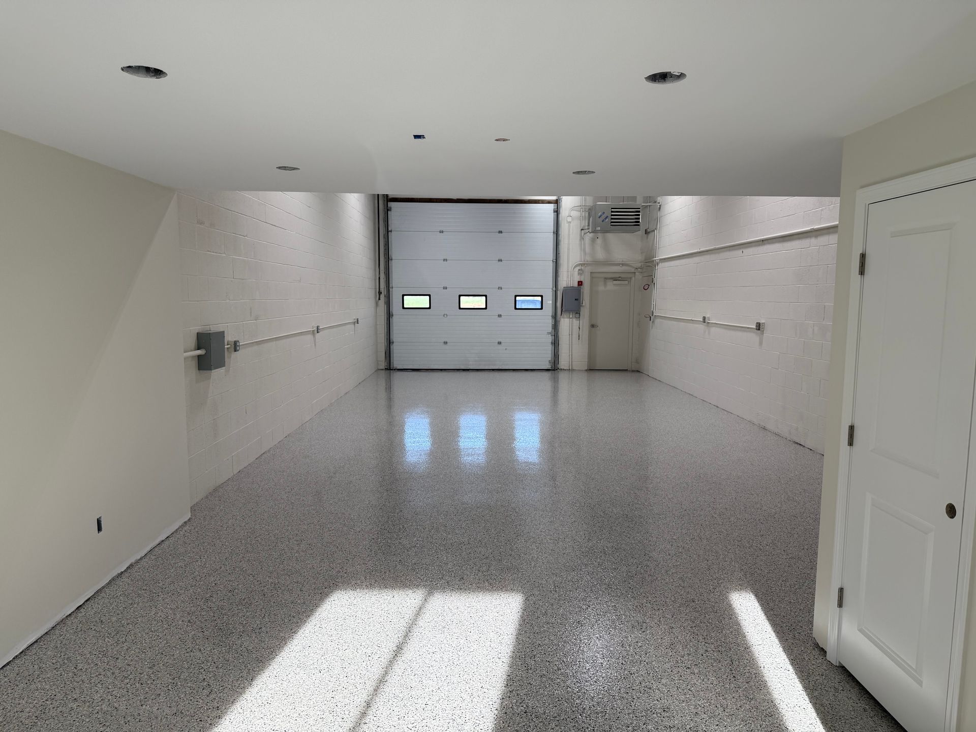 A long hallway with a garage door in the background