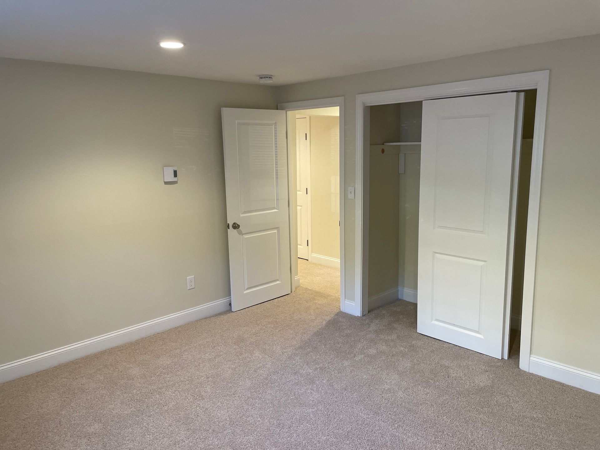 An empty bedroom with a closet and sliding doors.