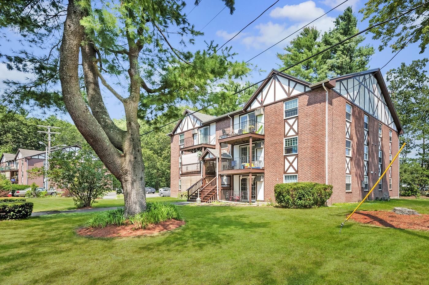 A large brick apartment building with a lush green lawn in front of it.