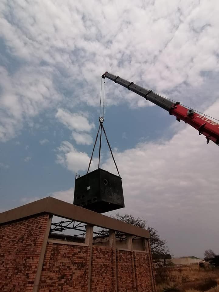 A Crane Is Lifting A Large Black Box On Top Of A Brick Building — All Lift Cranes In Ulladulla, NSW