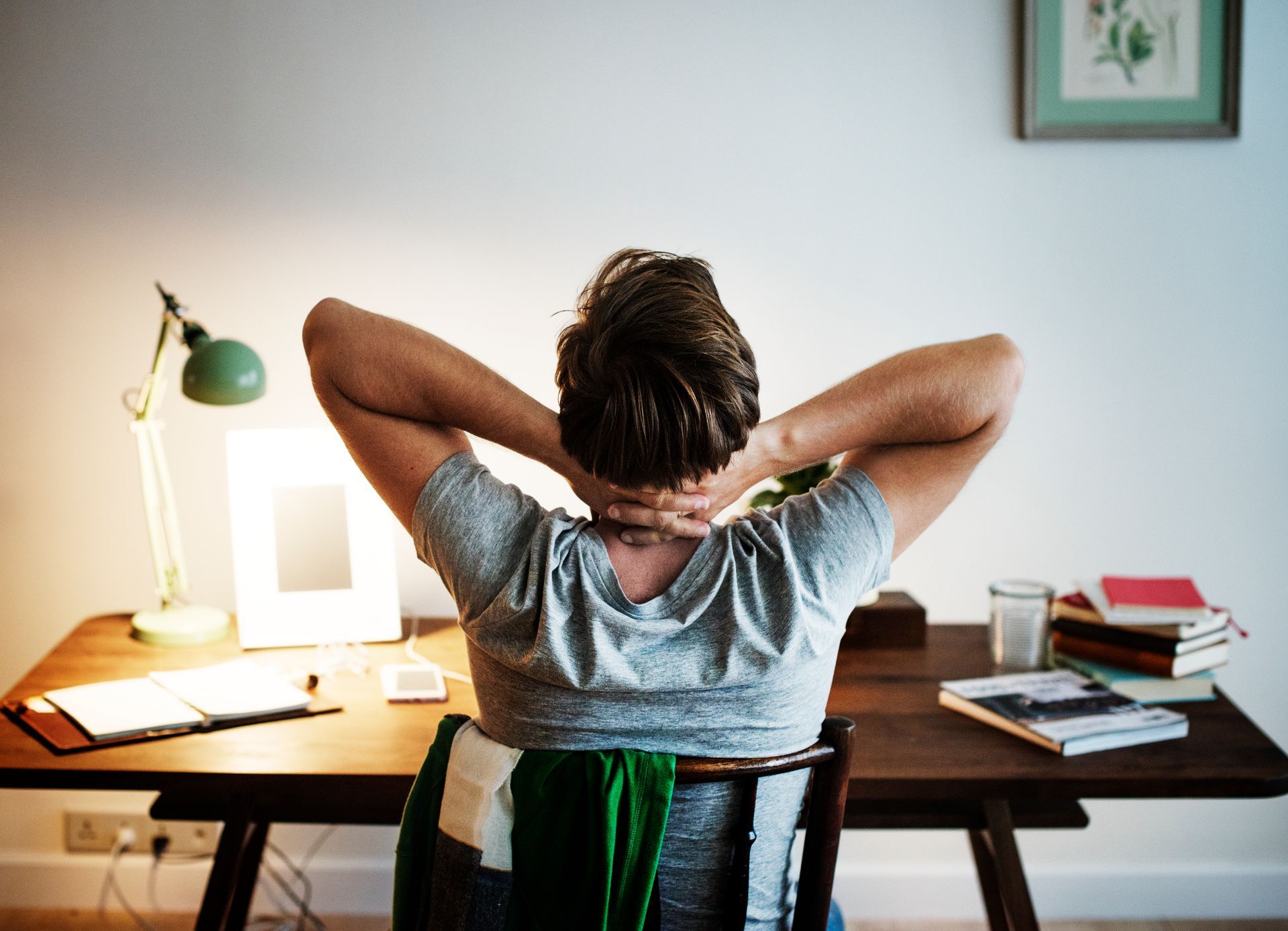 a man sits at a desk with his hands behind his head