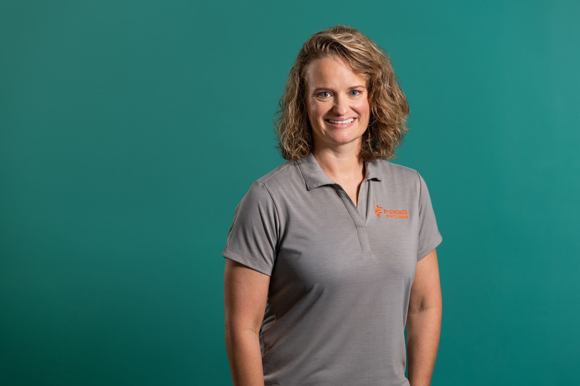 A woman with red hair is wearing a black shirt and smiling.