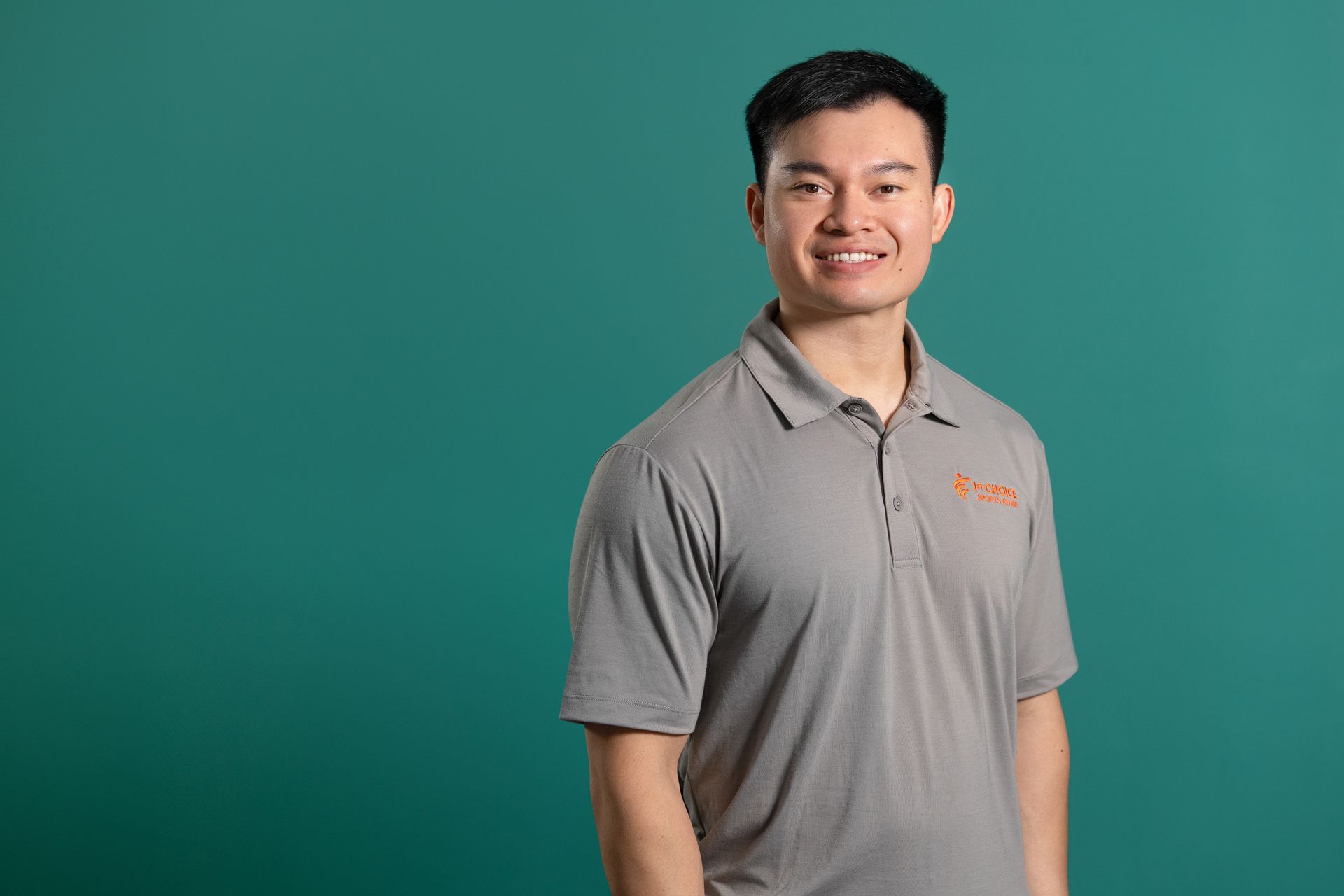 A man in a tan polo shirt is smiling for the camera