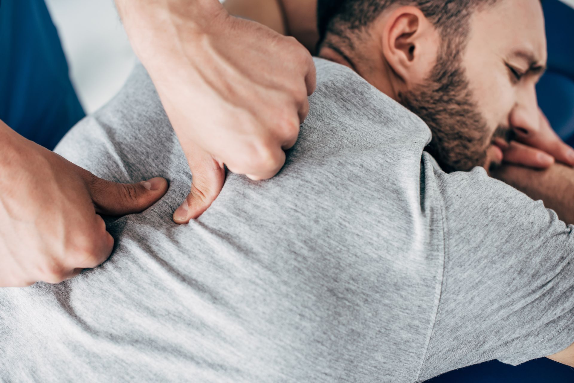 Chiropractor applying pressure to a patient’s back during a manual adjustment.