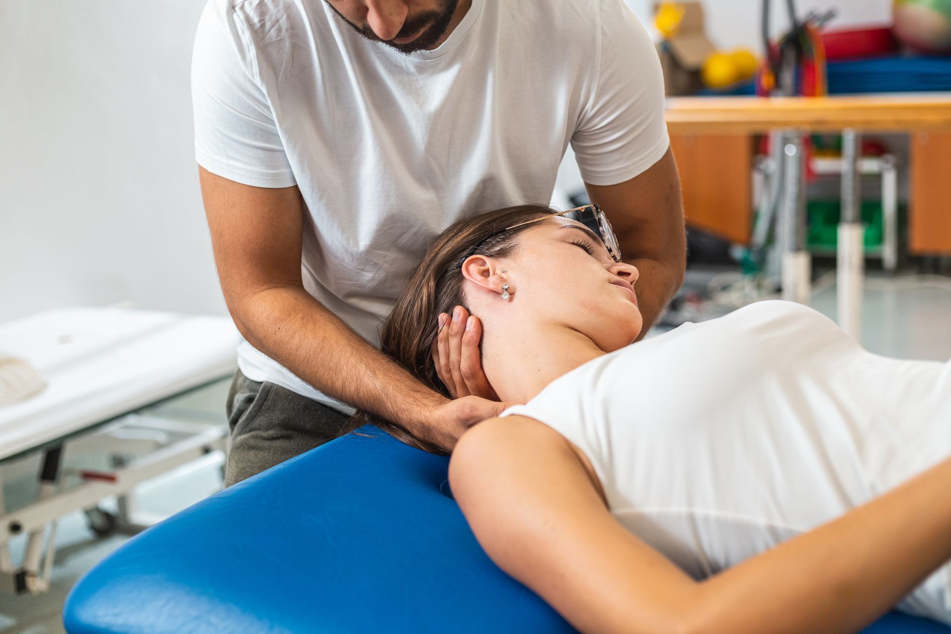 Chiropractor performing a neck adjustment as the patient lies on a treatment table.