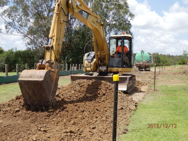 Worker Using Excavator to Dig in Field — Elmac Plant Hire In Taree