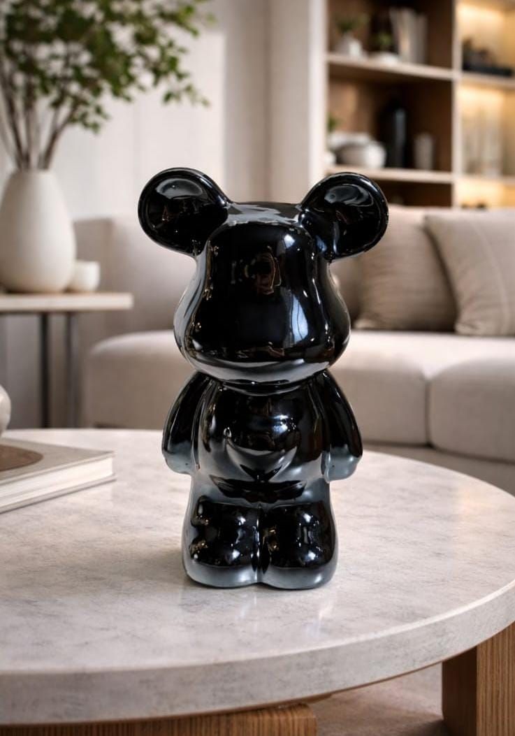 Una figurita negra brillante con forma de oso reposa sobre una mesa de centro redonda de mármol en una sala de estar moderna.