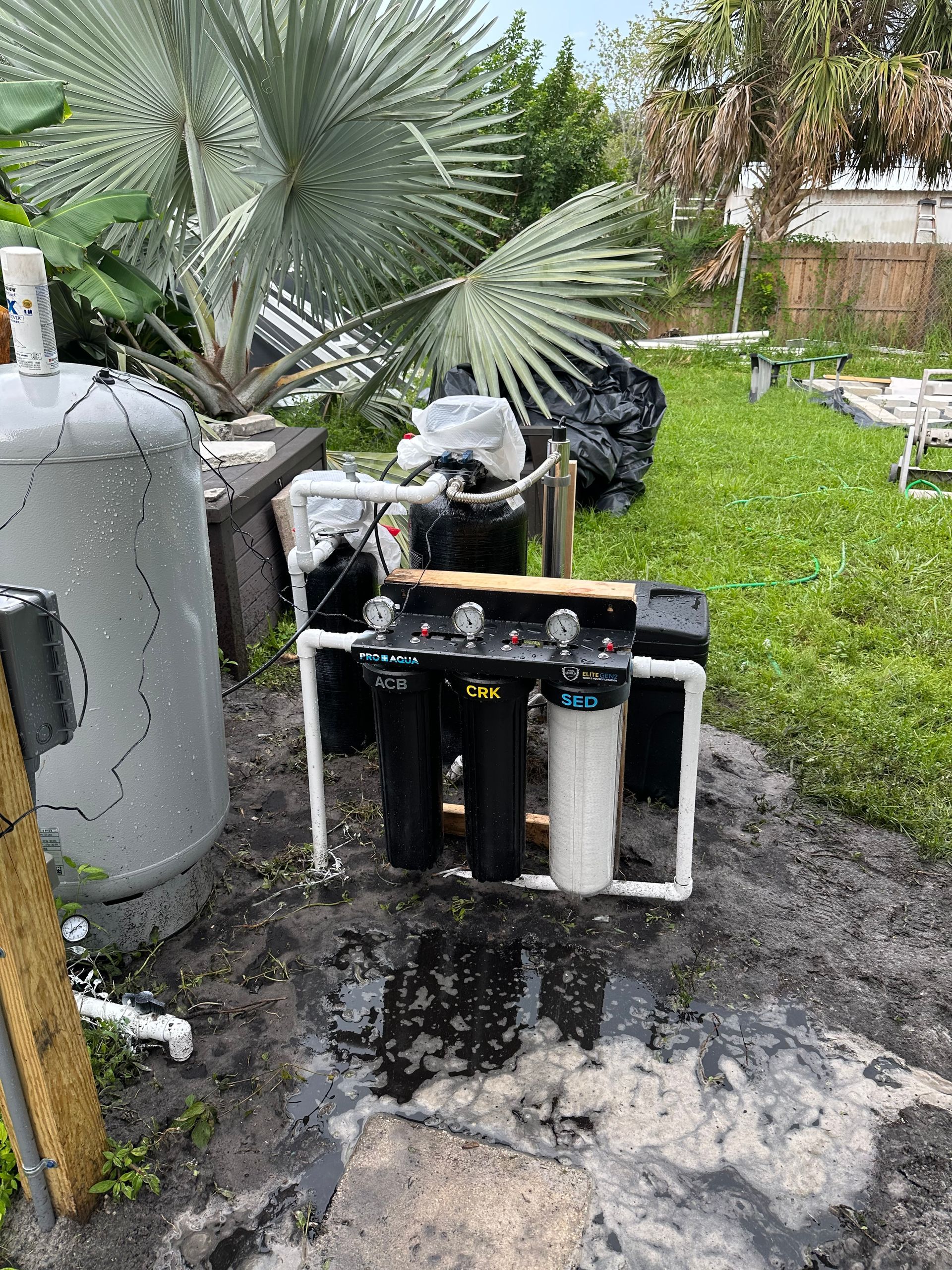 Hands using a wrench to adjust a fitting on a pipe with pressure gauges, near a white wall.