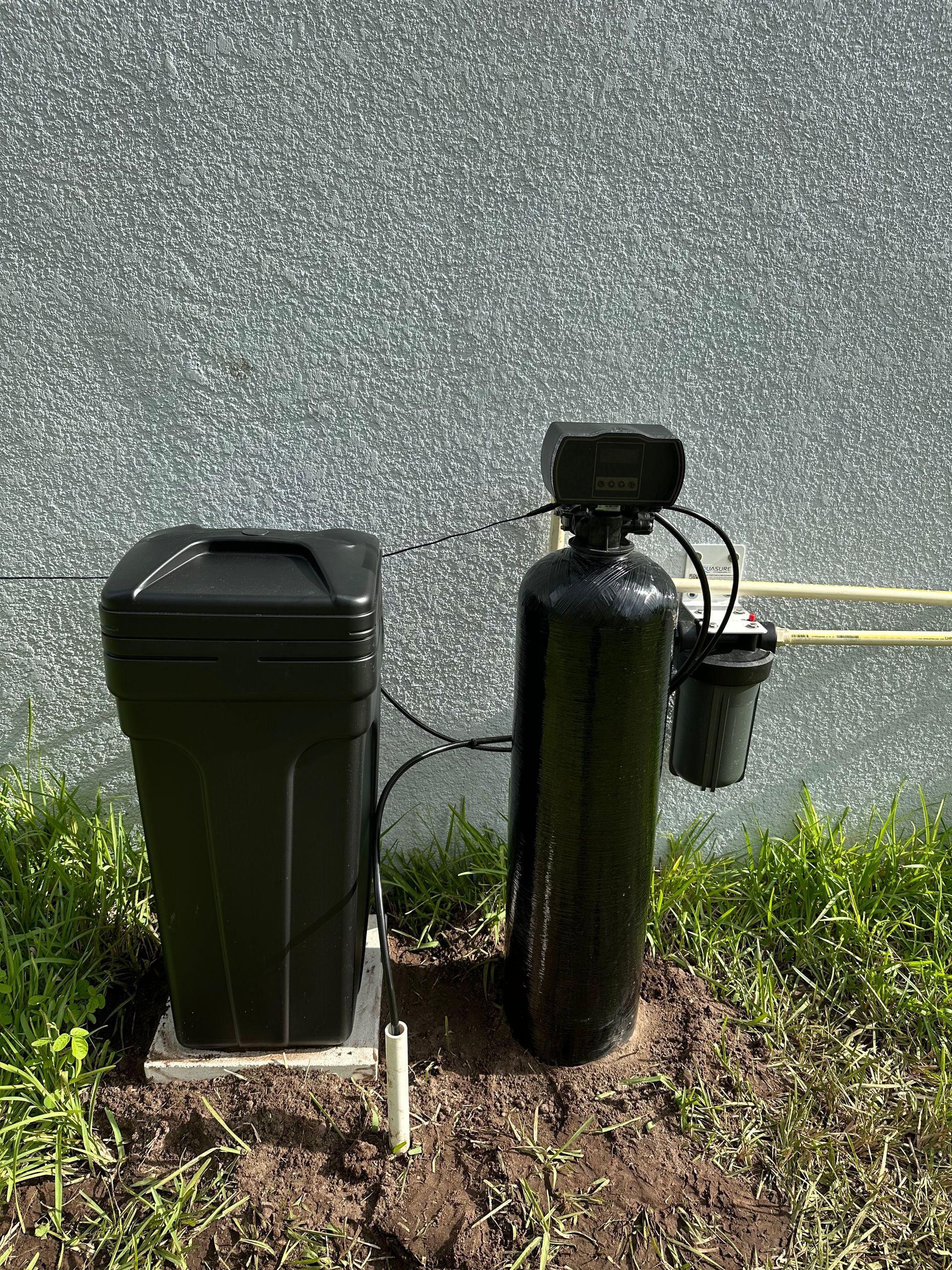 Person working on a water filtration system under a sink, using a screwdriver.