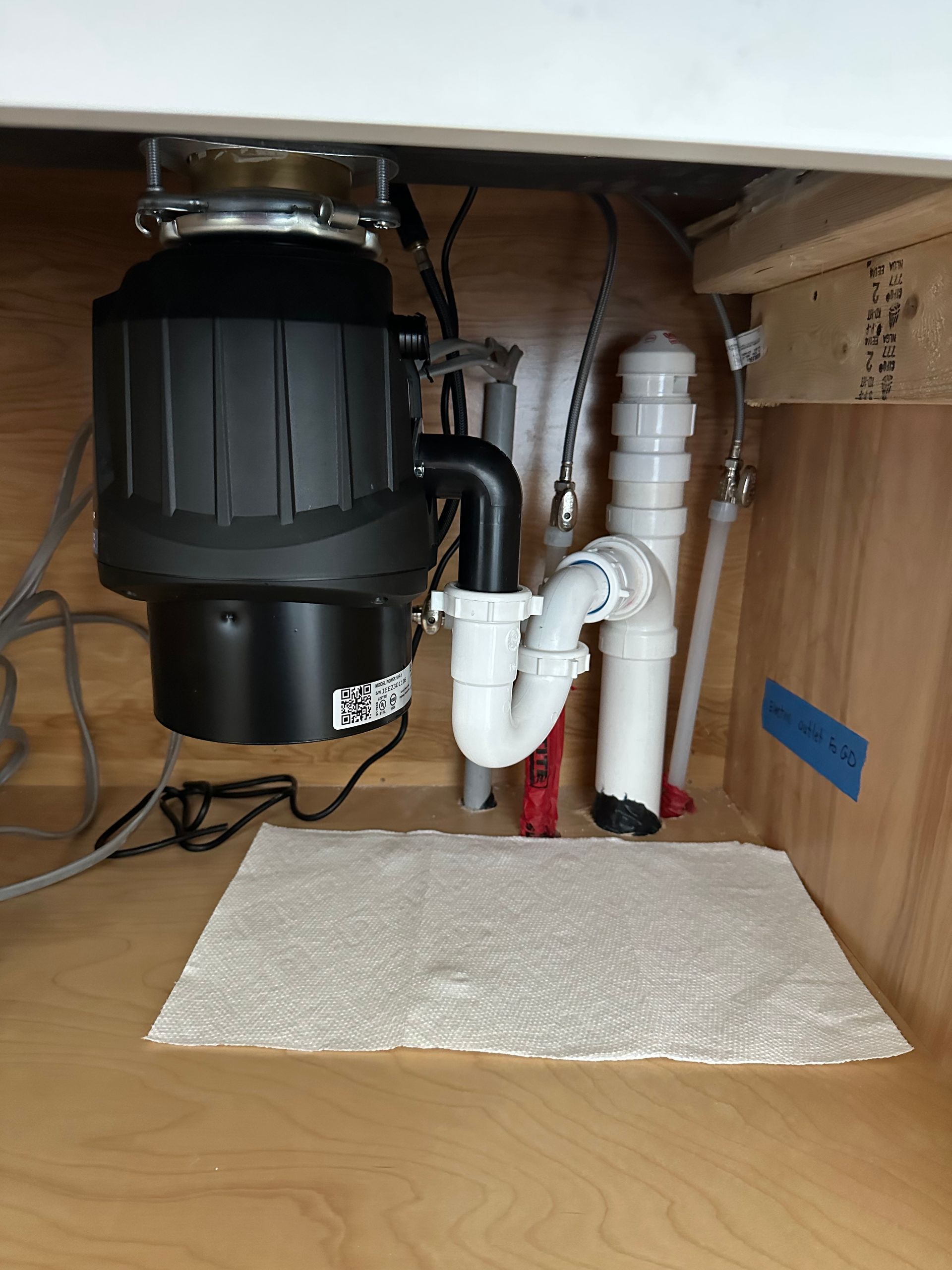 Plumber installing a bathroom vanity in a room with wood-look tile. Plumber installing a bathroom vanity in a room with wood-look tile.