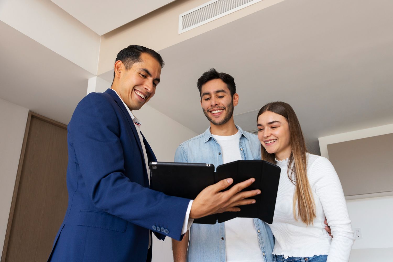 Man and woman in an office, reviewing papers. Man smiles, woman reaches to hand over a document.