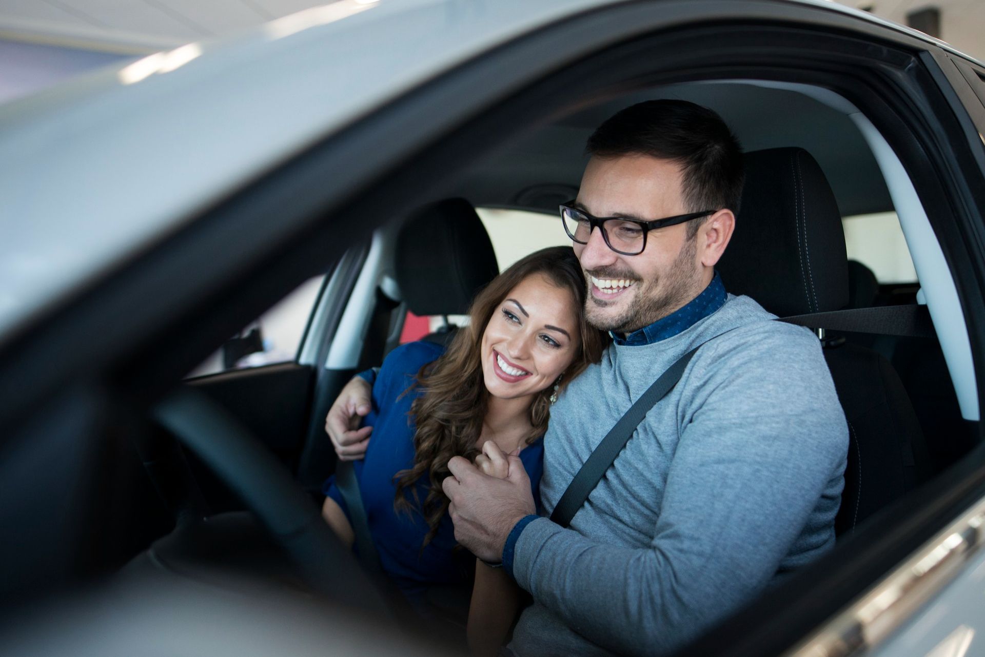 Family smiles inside a car, driving on a sunny day.