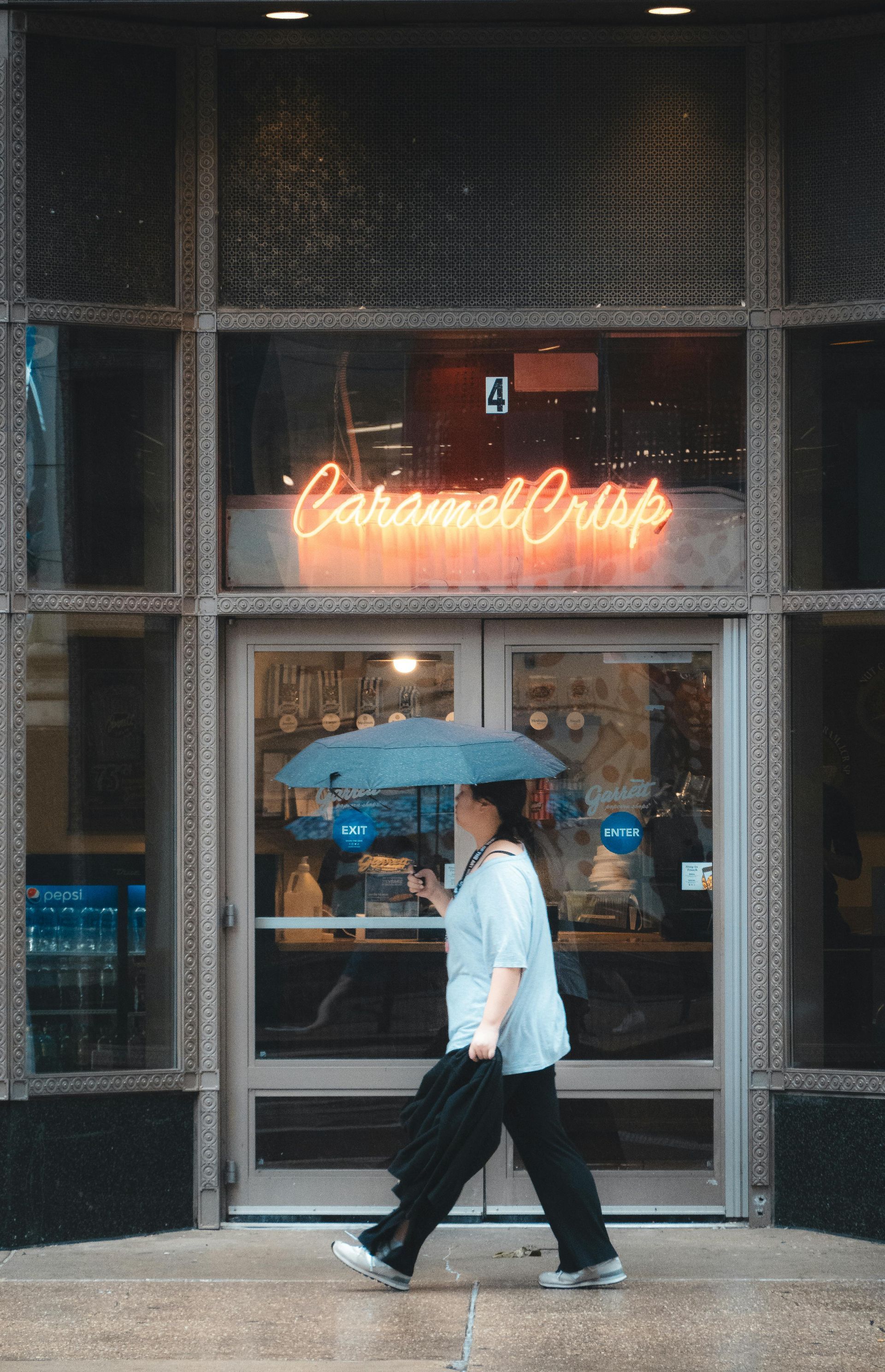 Family in a modern kitchen. Man holding a baby, woman smiling. Round table with laptop, large window.