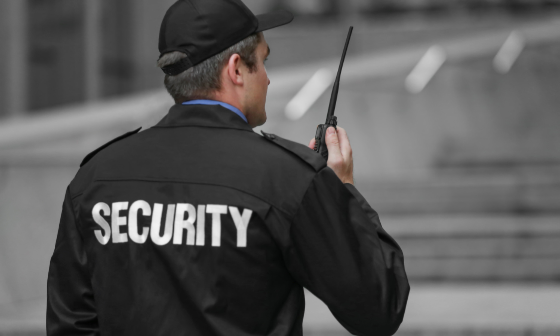 Security guard in black uniform, holding a walkie-talkie, with