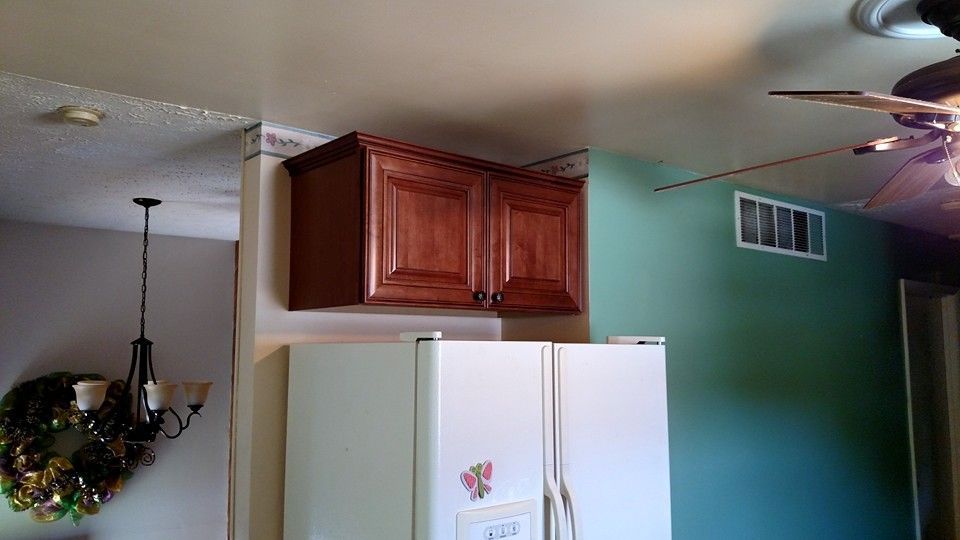 A kitchen with a refrigerator , cabinets , and a ceiling fan.