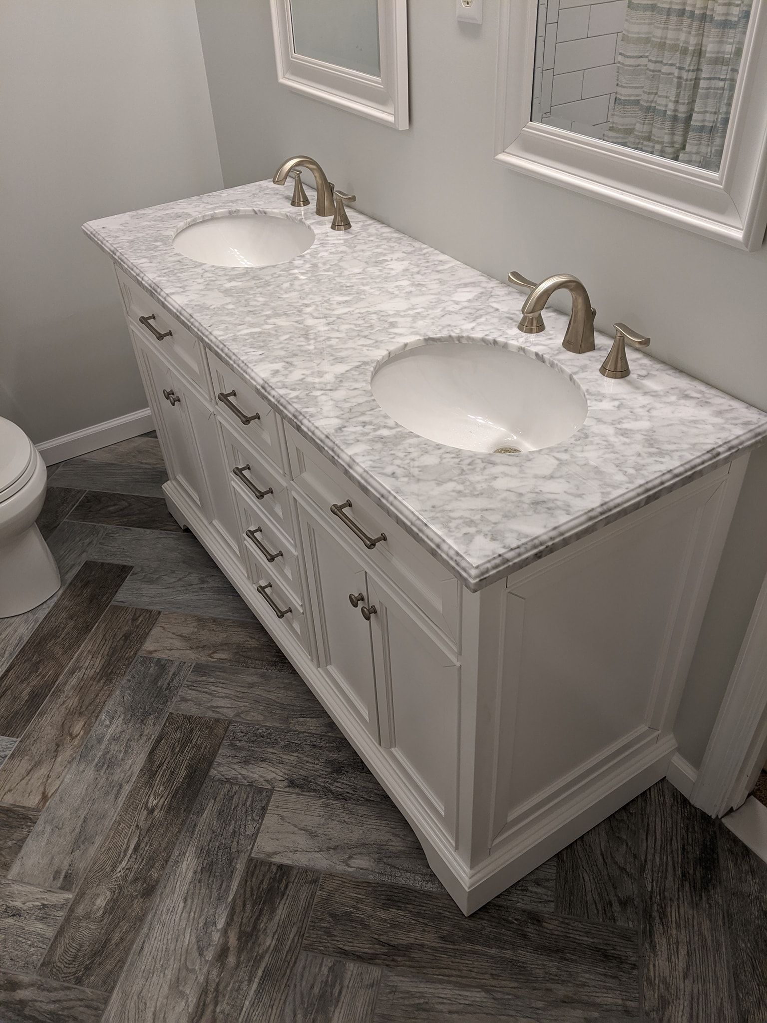 A bathroom with two sinks , a toilet and a mirror.