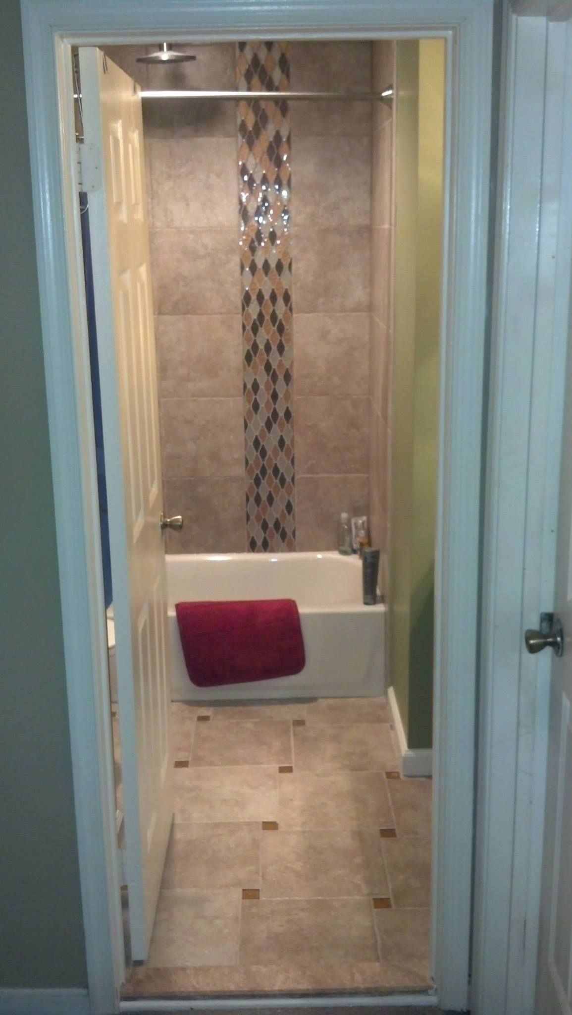 A bathroom with a bathtub and a red towel on the floor.