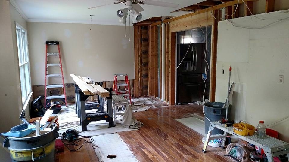 A living room is being remodeled with hardwood floors and a ceiling fan.