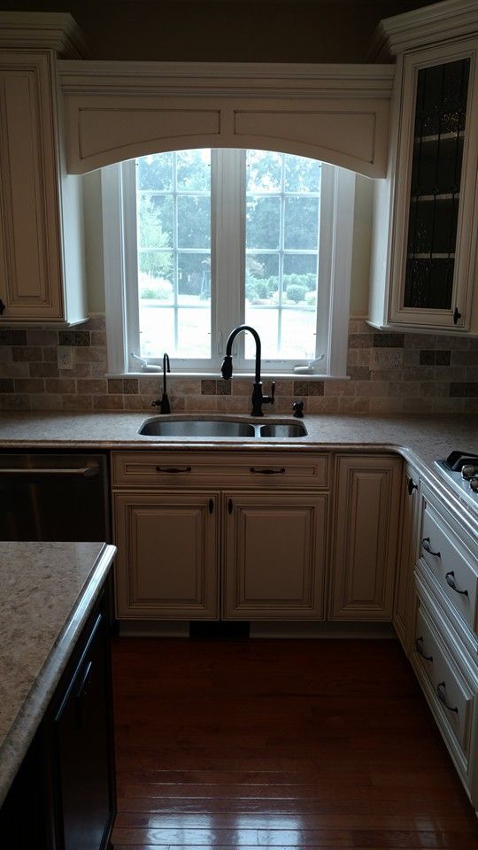 A kitchen with two sinks , a stove , and a window.