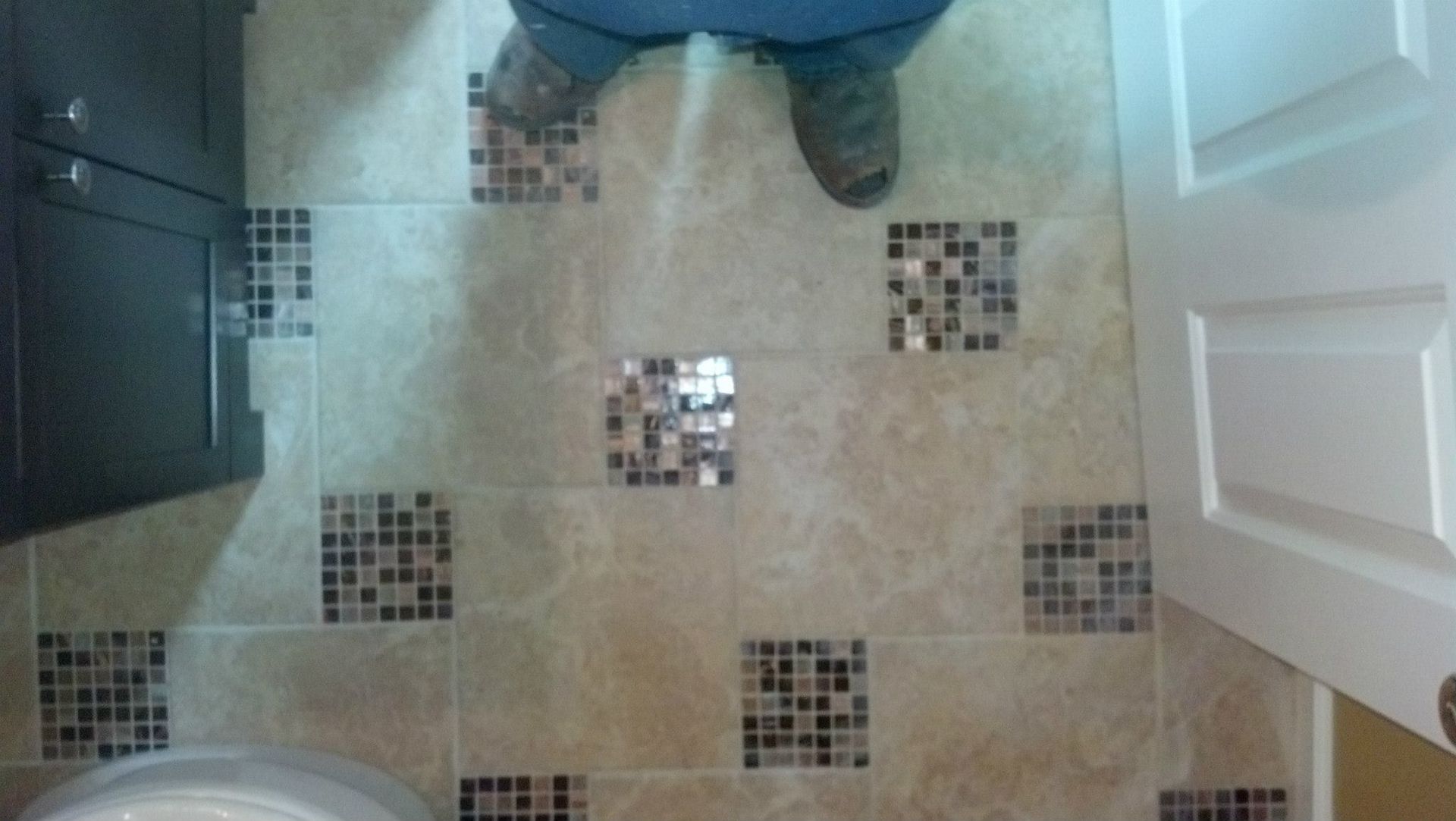 A person standing on a tiled floor next to a toilet