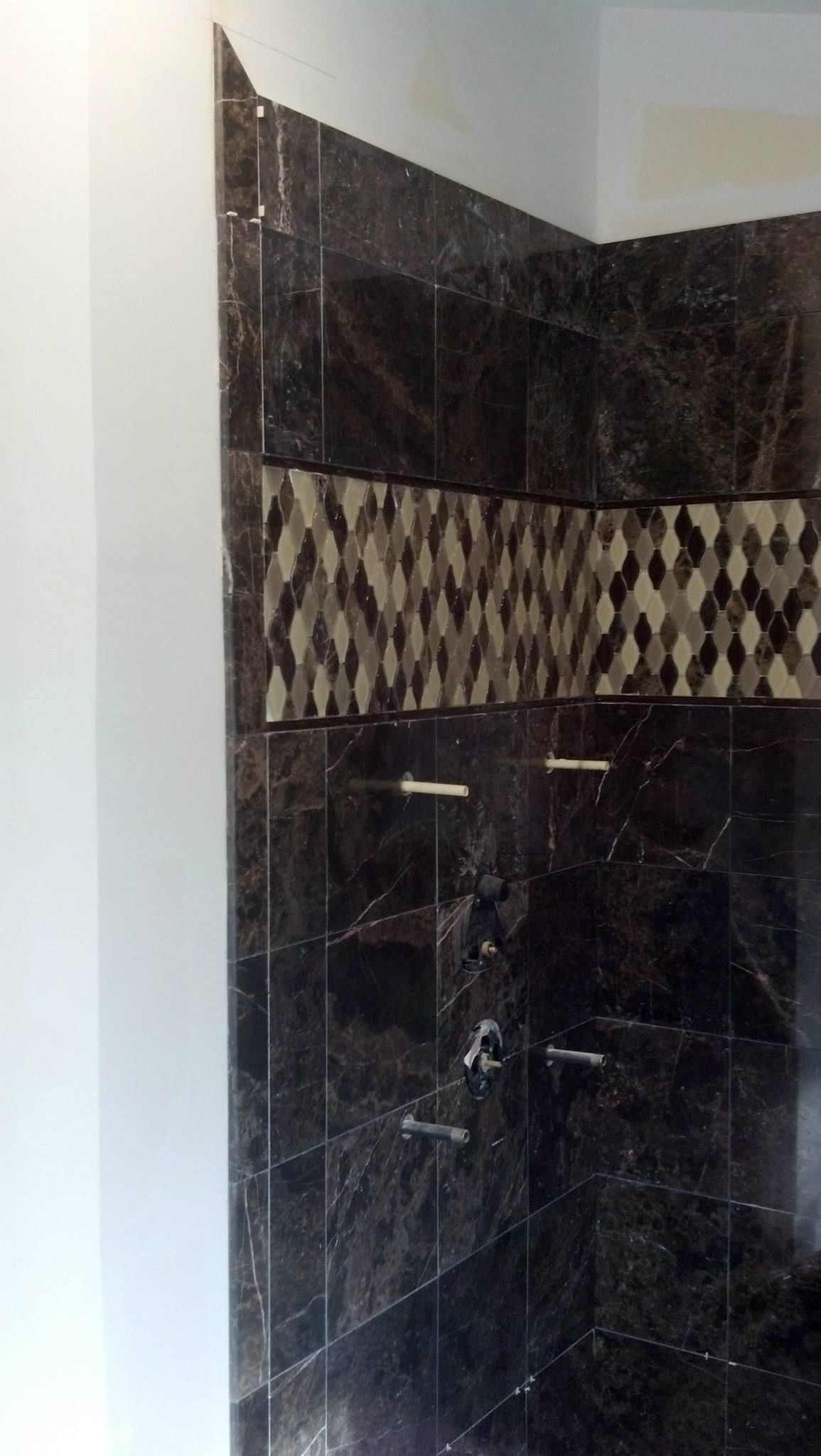 A bathroom with black tiles and a white wall.