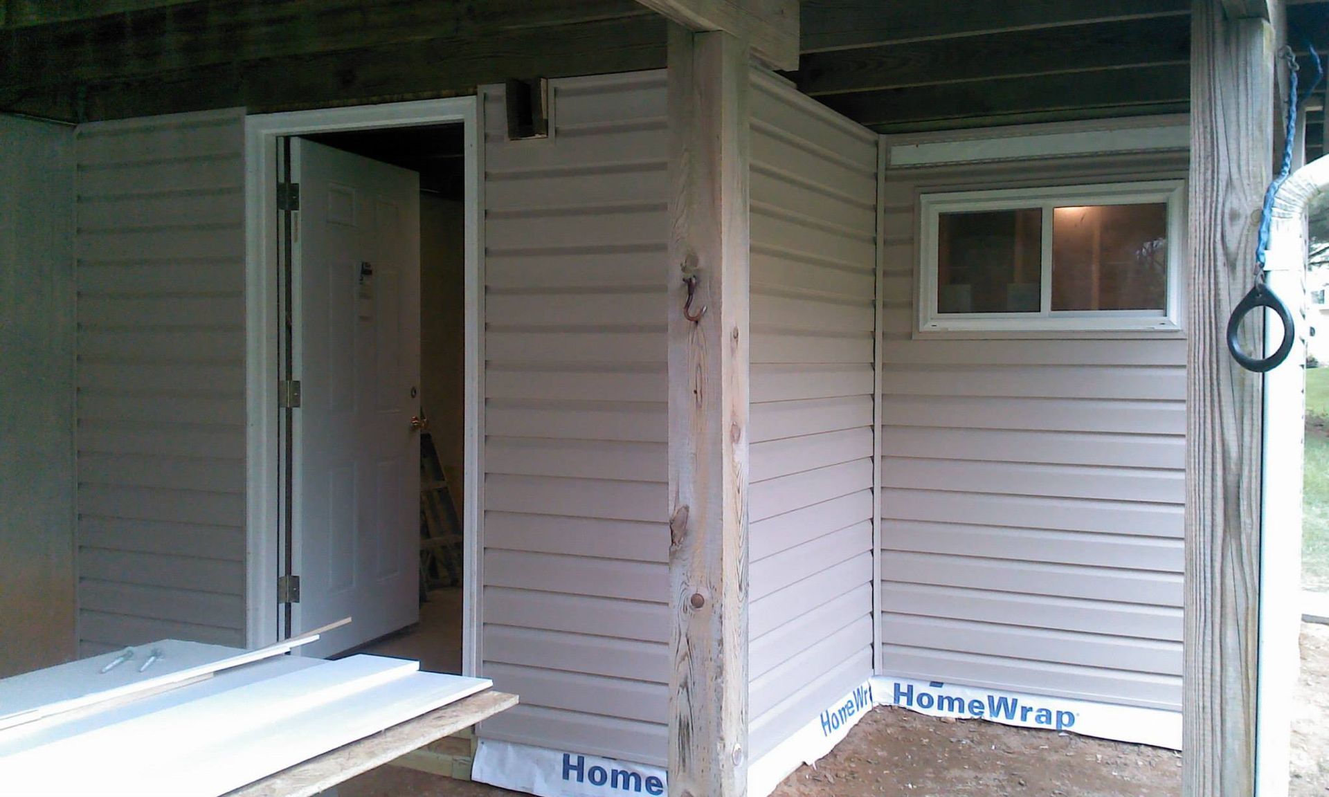 A corner of a house with a window and siding that says home wrap