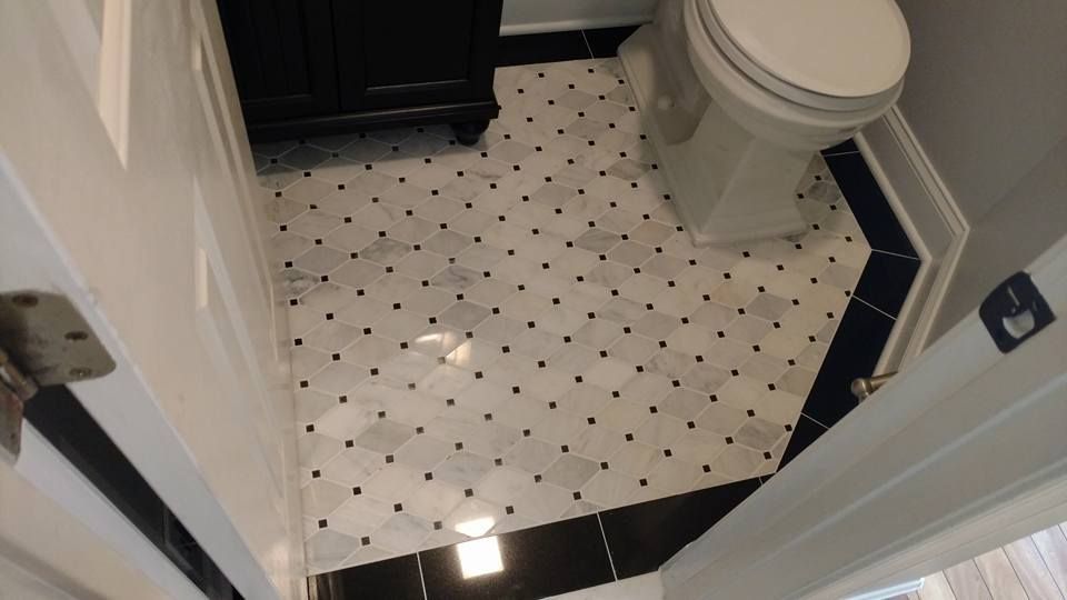 A bathroom with black and white tiles and a toilet