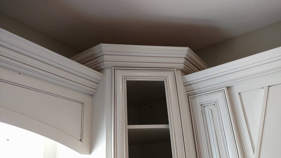 A corner of a kitchen with white cabinets and a window